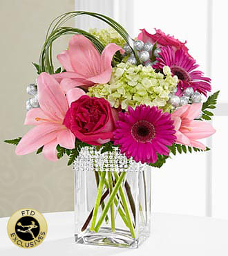 The FTD® Blooming Bliss™ Bouquet - BL2S  The FTD® Blooming Bliss™ Bouquet showcases blushing blooms and definitive style to send your special recipient a gift blossoming with heartfelt happiness. Hot pink roses and gerbera daisies are a standout in this bouquet surrounded by pale pink Asiatic Lilies and the alluring texture of green mini hydrangea blooms perfectly accented with bear grass blades and lush greens to create a simply stunning flower arrangement. Presented in a clear glass vase with silver beading lined at the top, this mixed flower bouquet is that perfect expression of love and kindness to send in honor of a birthday, as a way to express your thanks and gratitude, or in celebration of an anniversary. GOOD bouquet is approximately 12"H x 13"W.