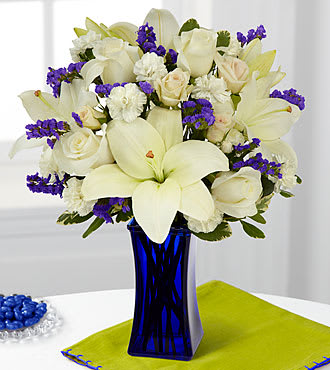 The FTD® Beyond Blue™ Bouquet - CDBS  The FTD® Beyond Blue™ Bouquet is a wonderful way to send peaceful wishes to your special recipient. Bringing together gorgeous white Asiatic Lilies, white roses (in Deluxe and Premium versions), and white mini carnations accented with blue statice, cream spray roses, and lush greens, this stunning bouquet captivates at every turn. Presented in a dark blue glass vase to contrast with it's bright white blooms, this beautiful flower arrangement will make an excellent thank you, get well, engagement or sympathy gift. Bouquet includes 9 stems with vase. Approx. 14"H x 12"W.