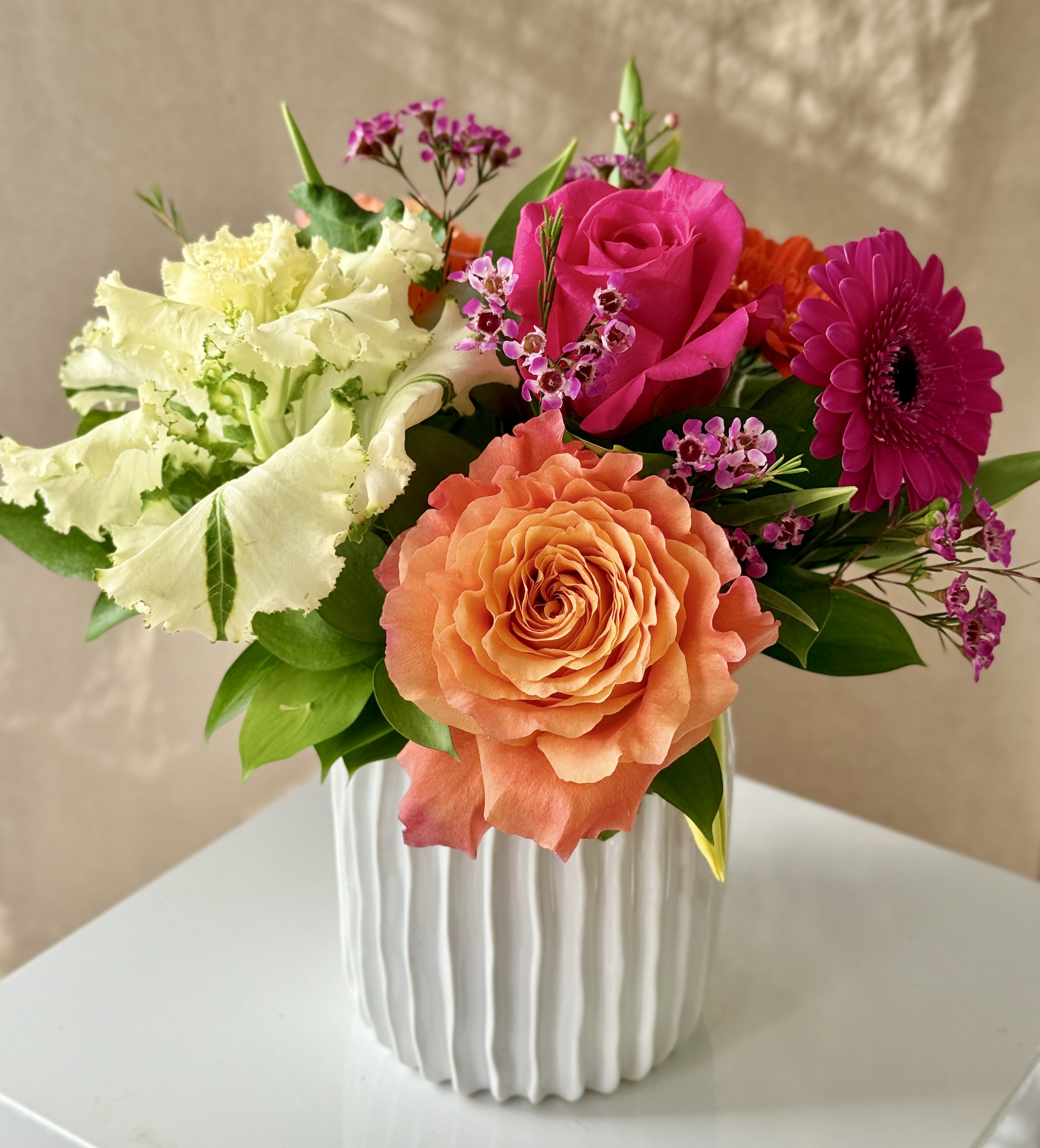 Abella - Spring with Tulips, Kale, Roses and Gerbera Daisies arranged in a ceramic vase.