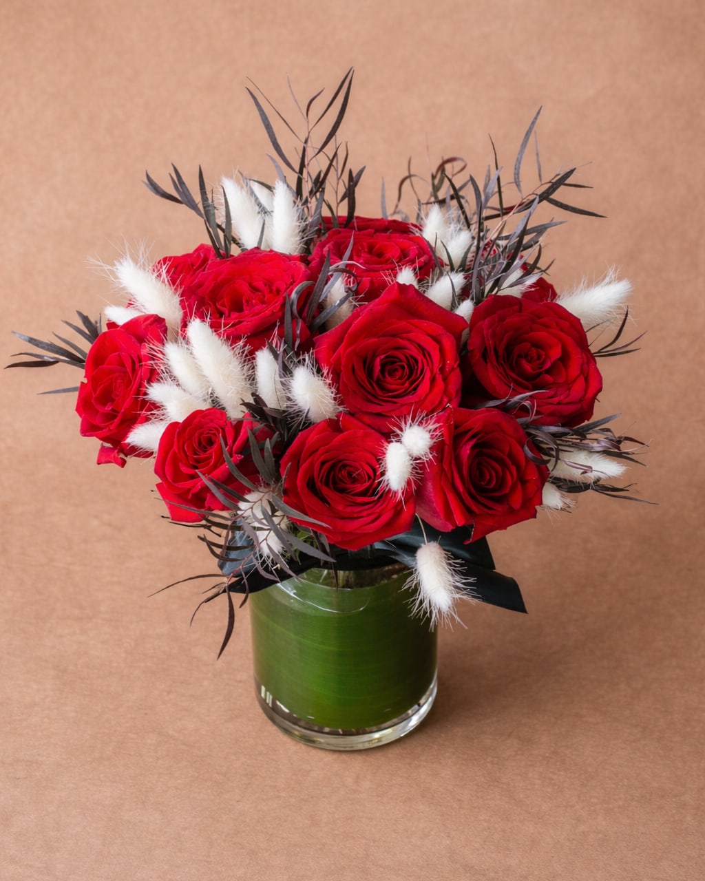 Christian - Dozen or more red roses in a medium height design arranged in a clear glass vase with unique accents. 