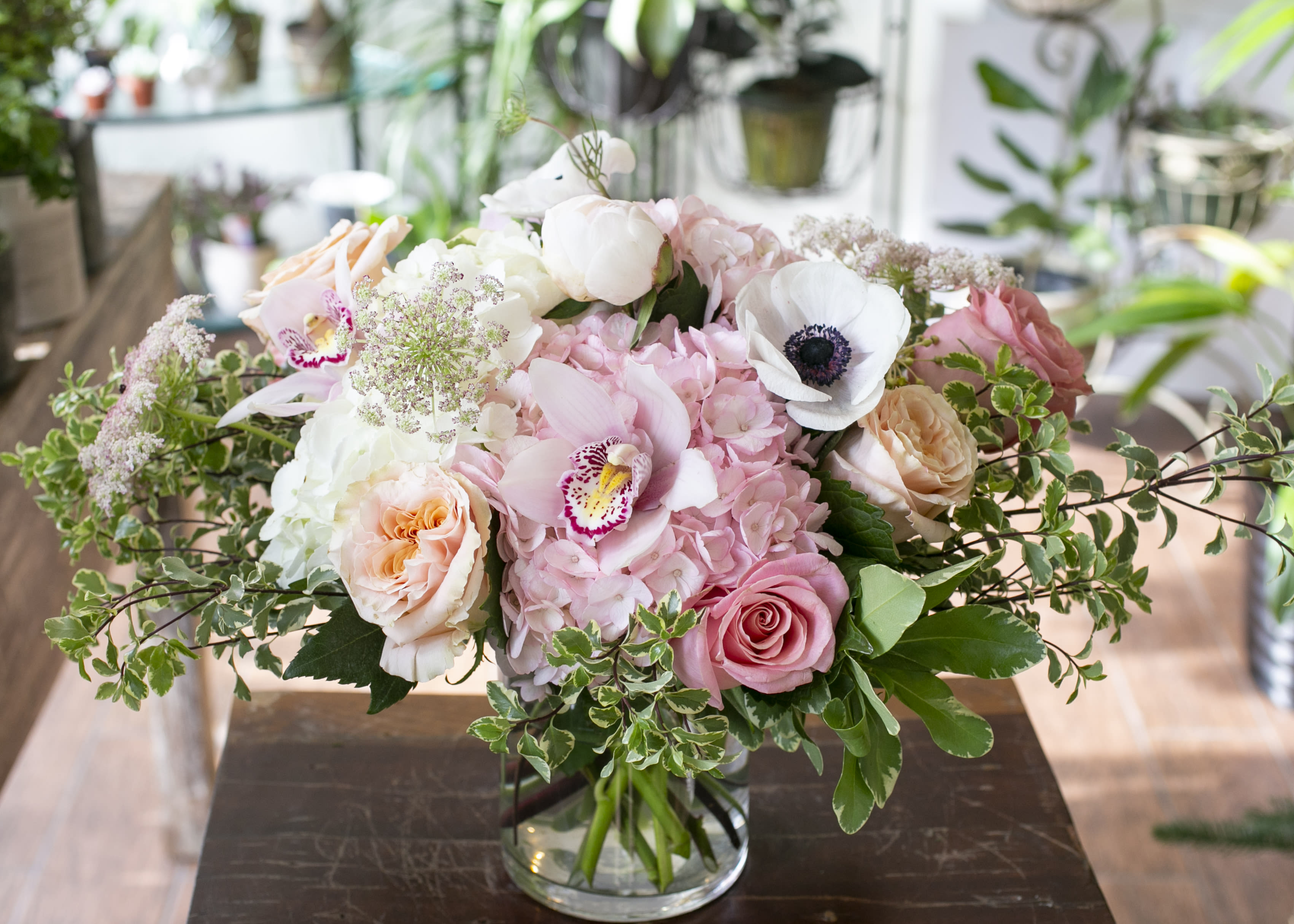 Vida - Monochromatic light pink flowers along with designer roses, arranged in a clear glass vase.