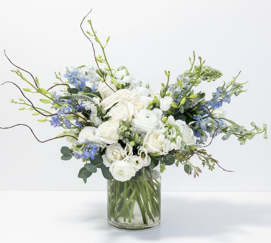 Blue Skies - This arrangement is a showstopper. It contains delphinium, ranunculus, roses, Lisi, stock, veronica and curly willow.