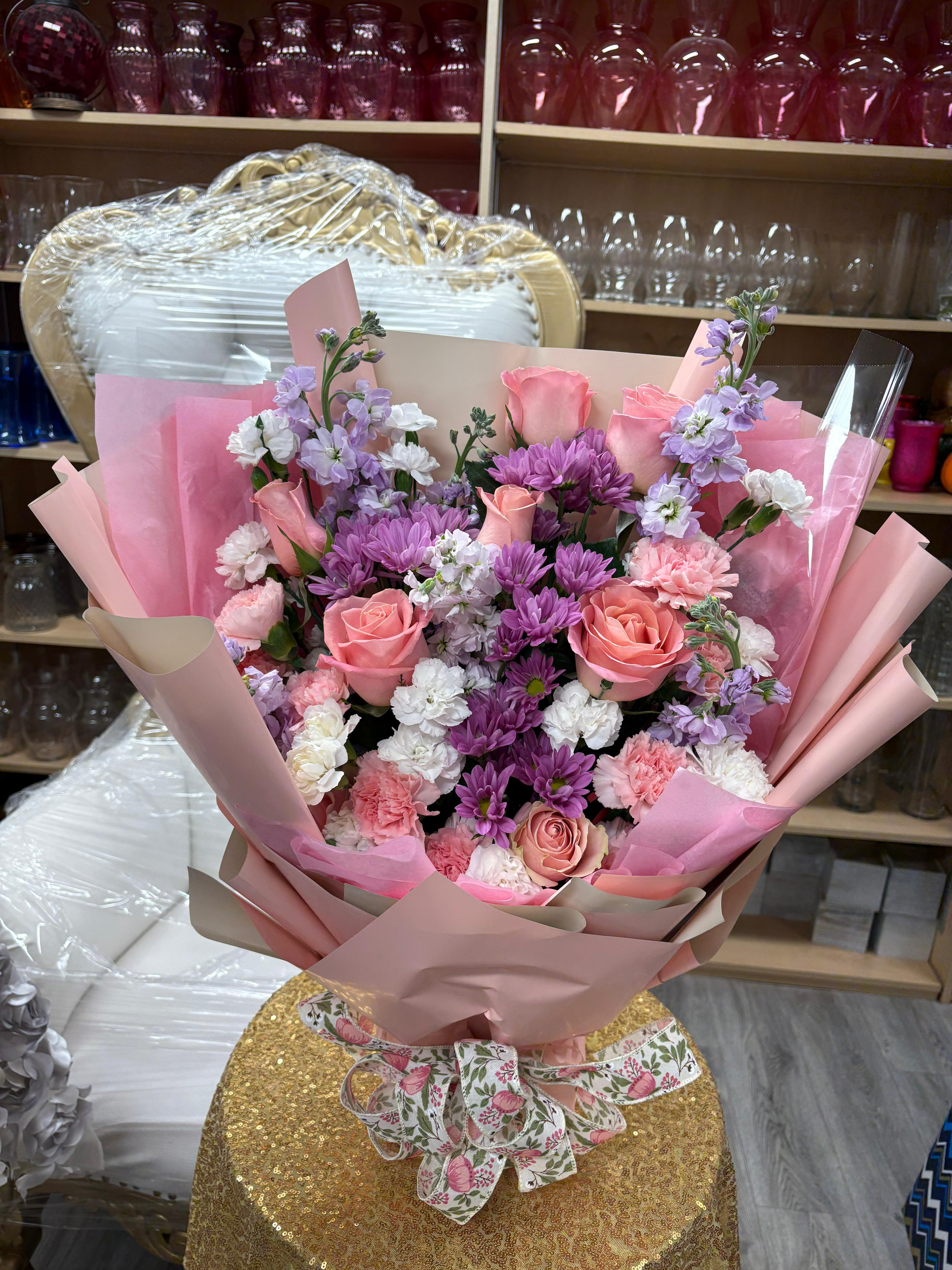 Blush Bloom - *Vase not included*  Floral arrangement crafted on oasis foam, in soft and fresh tones, combining 8 light pink roses, mini white carnations, mini pink carnations, 4 stems of stock, and daisies, creating a harmonious design with volume and a youthful style. Ideal for quinceañeras, birthdays, and special celebrations. 