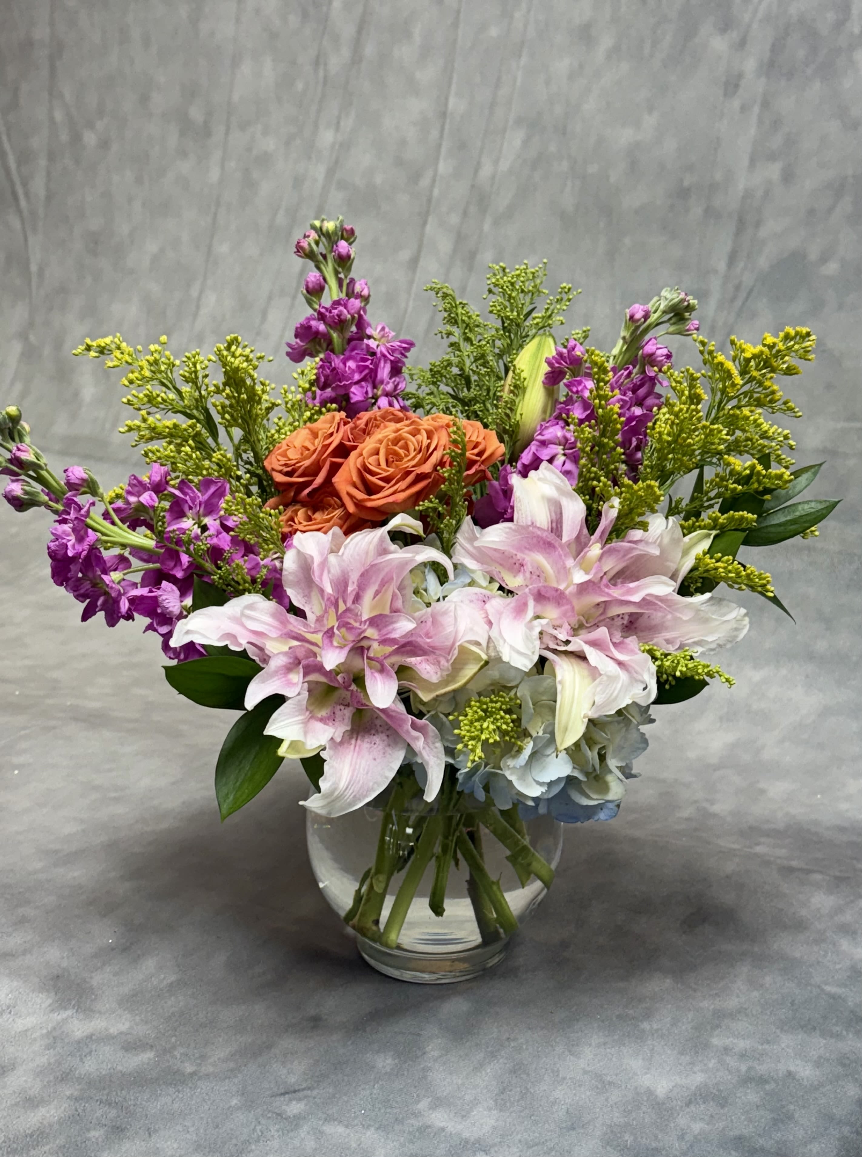 Flamingo Sunset - Flamingo Sunset is a vibrant floral arrangement bursting with warmth and elegance. Featuring lush hydrangeas, graceful lilies, striking snapdragons, and delicate spray roses in shades of pink, orange, and yellow. Perfect for brightening any space, celebrating a special moment, or simply bringing joy with its radiant charm.