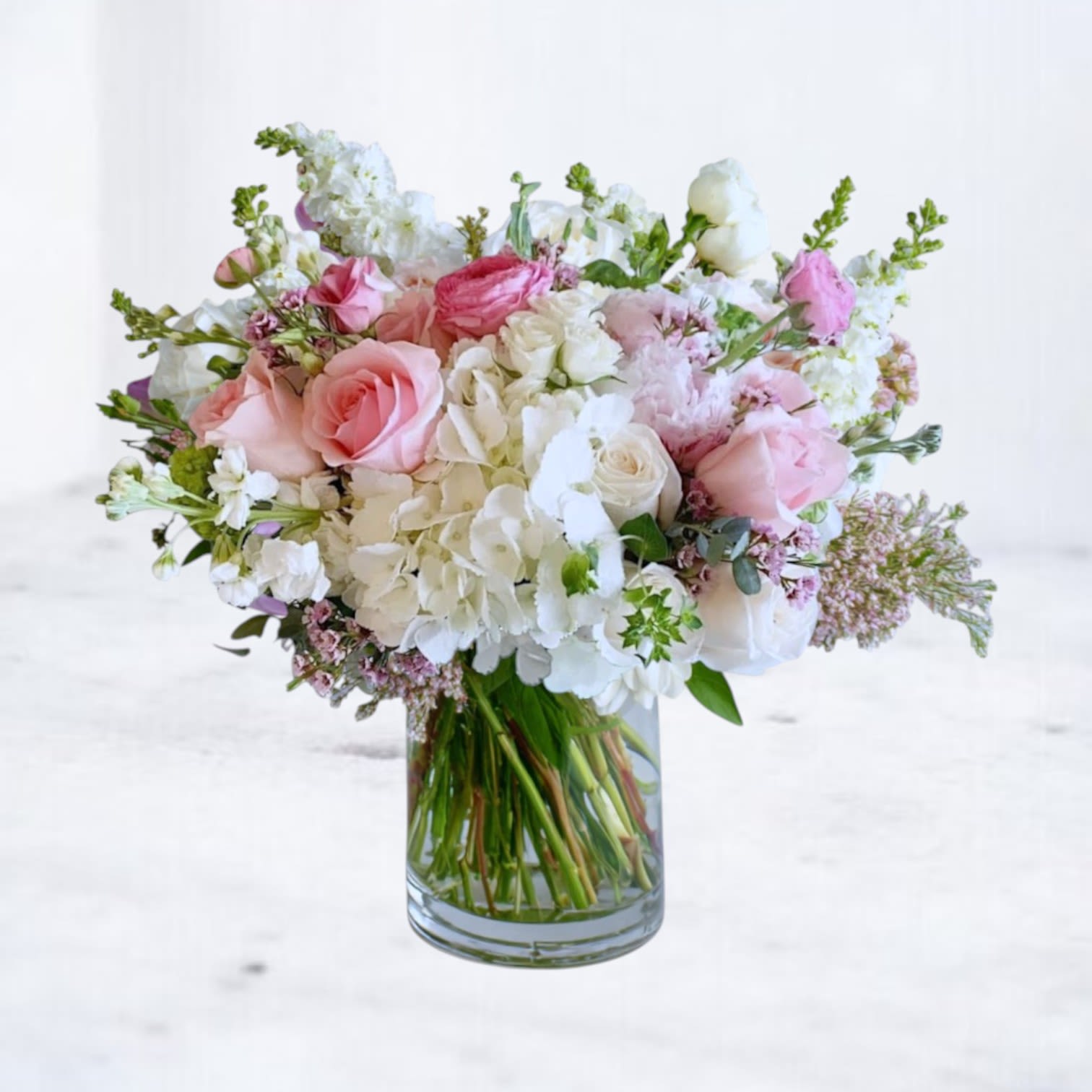 Blush Whisper - A delicate harmony of soft blush and creamy white blooms, the Blush Whisper Bouquet captures timeless elegance in every petal. Featuring roses, ranunculus, lush hydrangea, stock and lisianthus with fresh eucalyptus for texture and balance. Perfect for birthdays, anniversaries, sympathy gestures, or simply brightening someone’s day, this bouquet brings quiet sophistication to any space. Available for same-day delivery in Magnolia, The Woodlands, Spring, Montgomery, and surrounding areas.