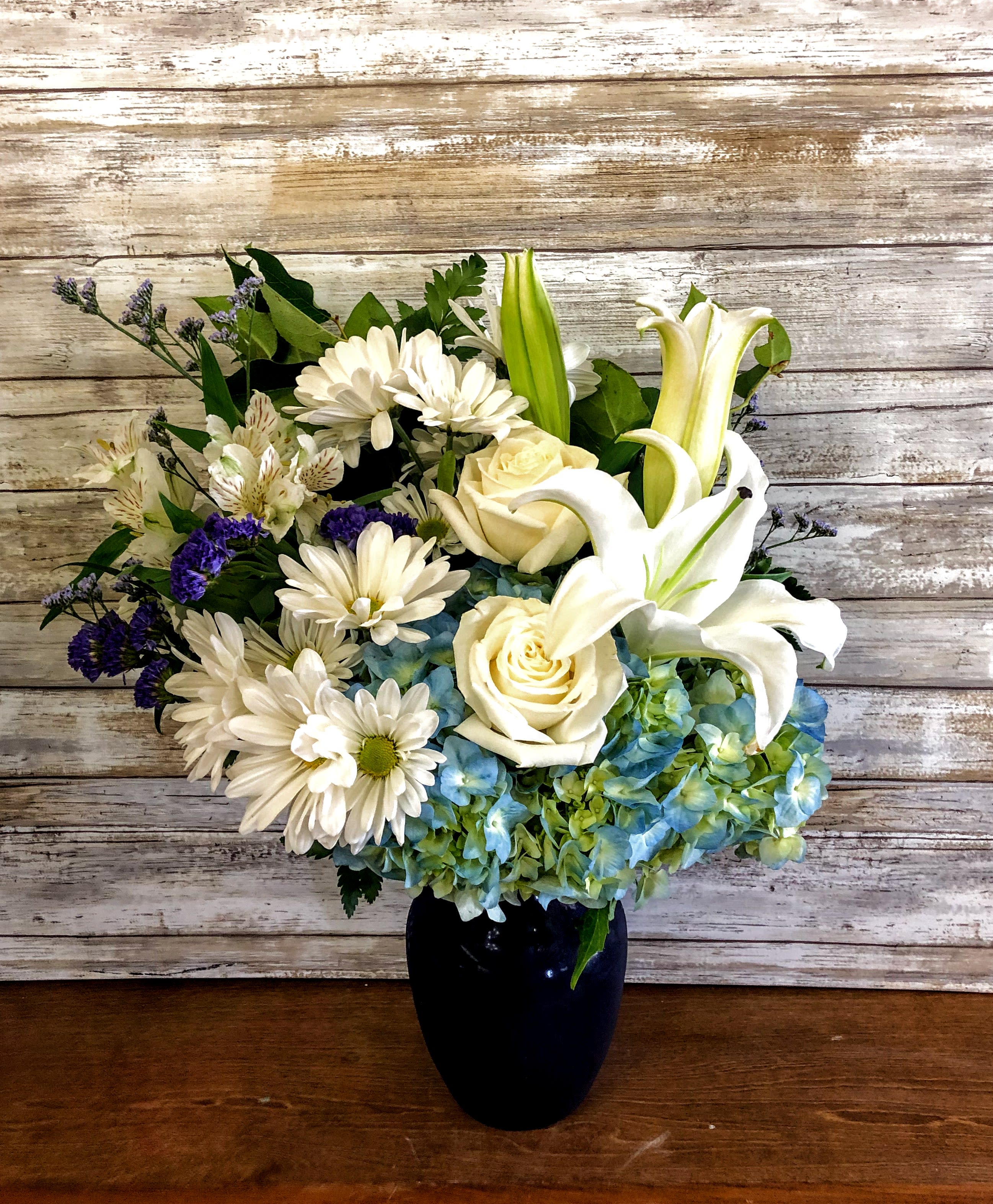 Beautiful in Blue  - In this arrangement, the serenity of the color blue along with the purity of intention symbolized by white will let the family know you are sending your calm strength to them during these difficult times. Approx. 20" H x 18 ½" W One-Sided Orientation 