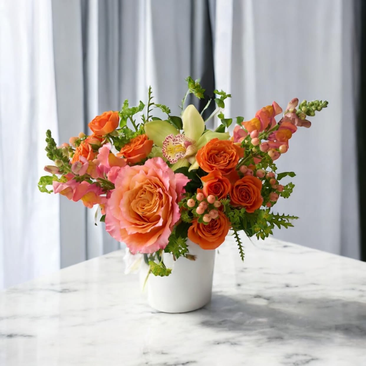 Sunset Radiance Bouquet - Bright, bold, and full of charm, our Sunset Radiance Bouquet is a luxurious floral arrangement designed to bring warmth and joy to any space. Featuring lush orange roses, soft coral snapdragons, romantic peach garden roses, and an elegant orchid, this bouquet captures the brilliance of sunset. Accented with fresh greenery and seasonal berries, it’s artfully arranged in a sleek white vase for a modern yet timeless presentation.  Perfect as a birthday bouquet, anniversary gift, corporate flower arrangement, or elegant centerpiece, this vibrant design is sure to make a lasting impression. Handcrafted with only the freshest blooms by Bloom in Glory Florist in Orlando, the Sunset Radiance Bouquet is available for same-day flower delivery across Orlando, Winter Park, Lake Mary, and surrounding Central Florida communities.  Whether you’re sending flowers to celebrate life’s special milestones or decorating your home with luxury florals, this radiant design is the ultimate choice for elegance, joy, and unforgettable beauty.