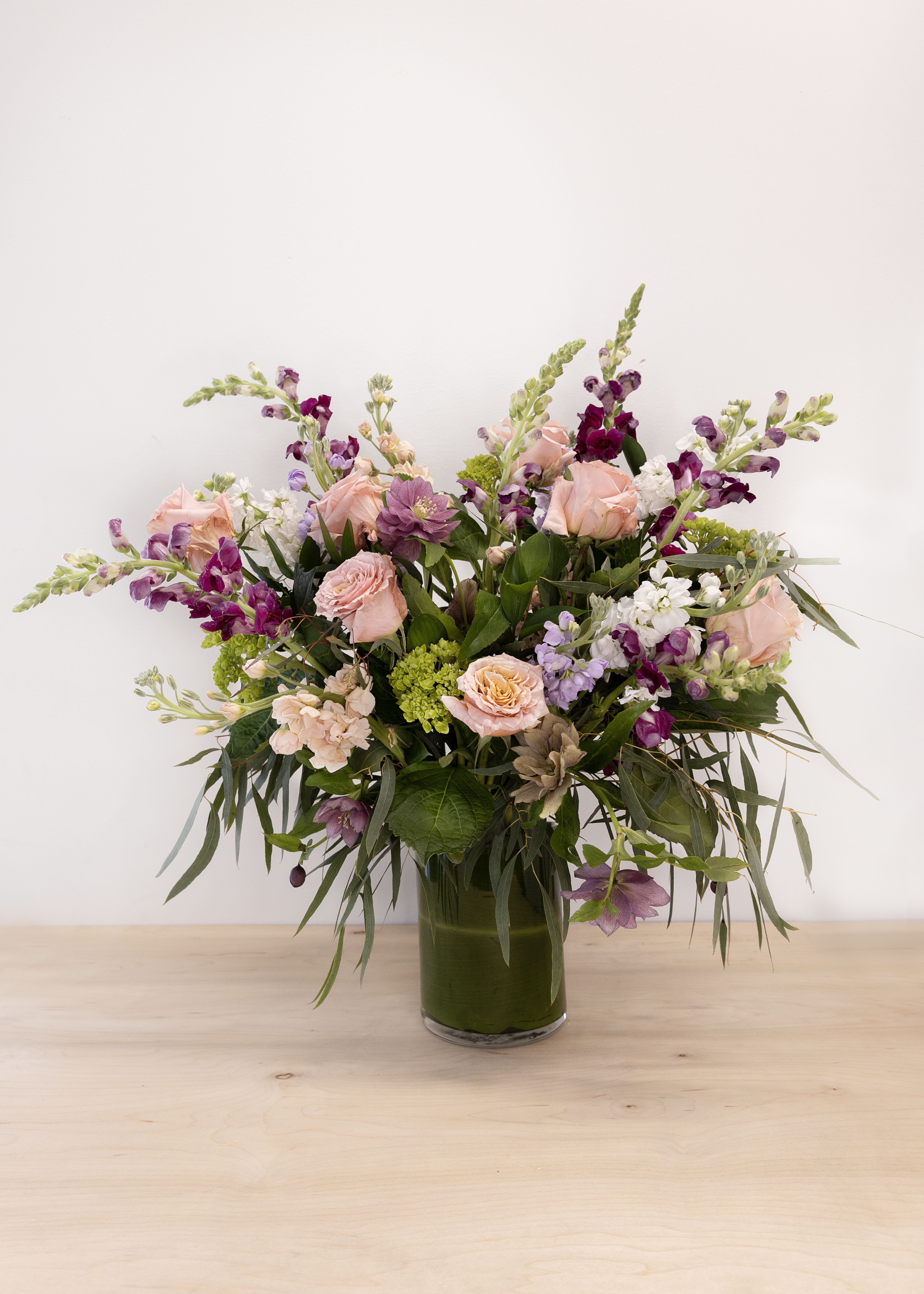 The Country Garden - This stunning arrangement of Garden favorites is sure to make a statement.  Bells of Ireland, Daisies, Hydrangea, Roses, Stock, and a mix of fresh variegated greens makes for a large counter or buffet presentation.    Standard option is approximately 16" x 30" in size