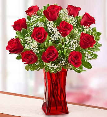 12 Red Roses In Red Vase  - Surprise the one who makes you smile most with our stunning bouquet of one dozen fresh red roses. Arriving in bud form for lasting beauty, this classic gift will help you express yourself perfectly, no matter what you are trying to say.
