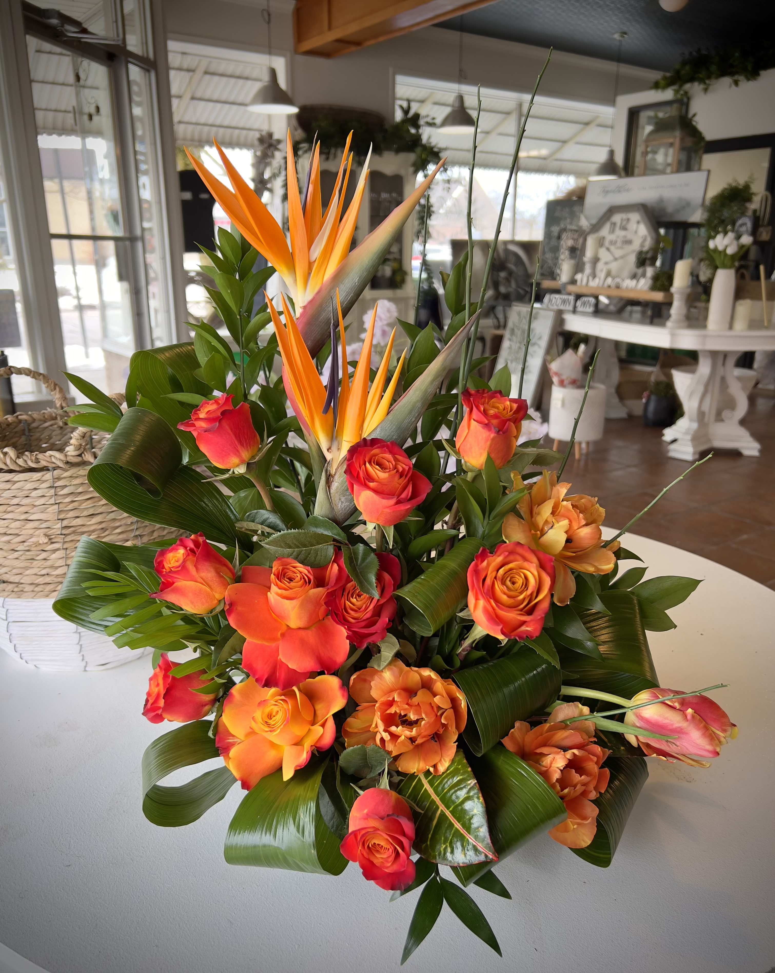 Away to Paradise  - Crafted with care, This vibrant funeral arrangement features stunning birds of paradise paired with cheerful orange roses. The exotic birds symbolize joy, while the orange roses express admiration and warmth. Perfect for honoring a loved one, this arrangement brings a burst of colour and comfort, creating a beautiful tribute that celebrates life and cherished memories. (Arrangement may be subject to substitution due to availability of flowers) 