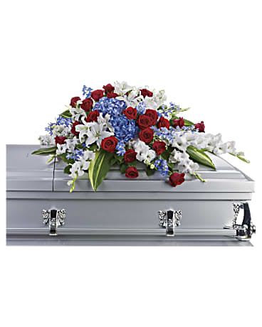 Teleflora's Distinguished Service Casket Spray  - For a military or private funeral, this classic half-couch casket spray is a proud and patriotic way to pay lasting tribute to an loved one's esteemed memory, life of service and dedication to freedom. Bold flowers such as blue hydrangea and delphinium, classic red roses, and white oriental lilies and gladioli form an all-American display honoring the deceased and their love of country. Orientation: One-Sided  SUBSTITUTION POLICY – Always deliver the freshest flowers! Please note the bouquet pictured reflects our original design.  If the exact flowers or container in this arrangement are not available, our local florists will create a beautiful bouquet with the freshest available flowers.