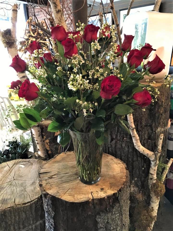 2 Dozen Red Roses - Two dozen red roses artfully designed in a  large clear glass vase with assorted premium greenery and white waxflower. *Regular price is 2 dozen roses with baby’s breath and standard greenery*