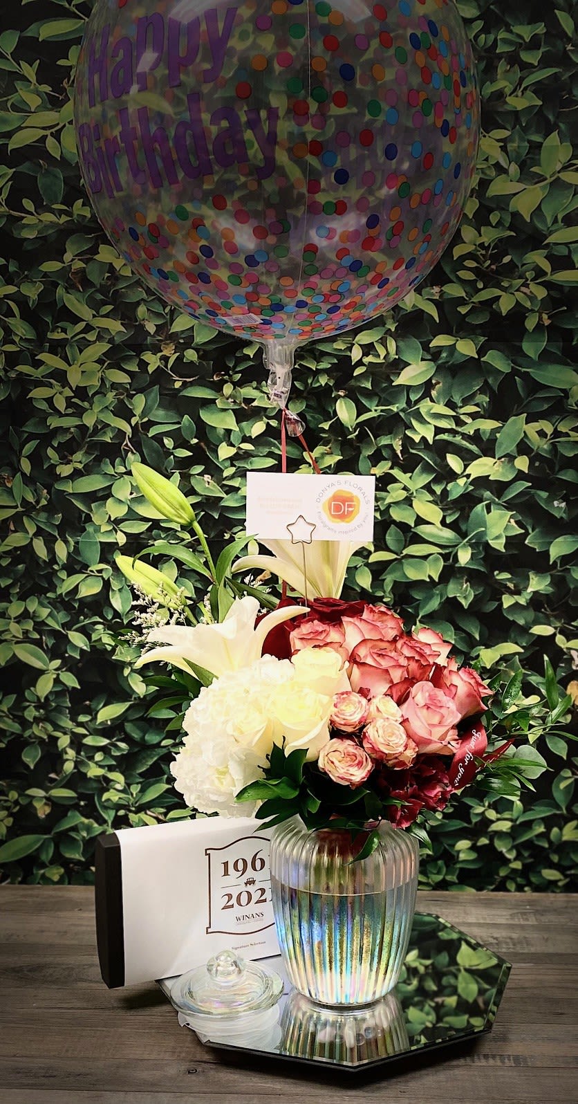 Forever Yours Rose Bouquet Gift Set, by Donya's Florals - More than a bouquet, the Forever Yours is a curated experience. A beautiful arrangement of roses is elegantly accompanied by chocolates, a candle, and a luxe balloon. Adorned with complimentary floral wrapping, it is made profoundly personal with your card—a stunningly complete gift.