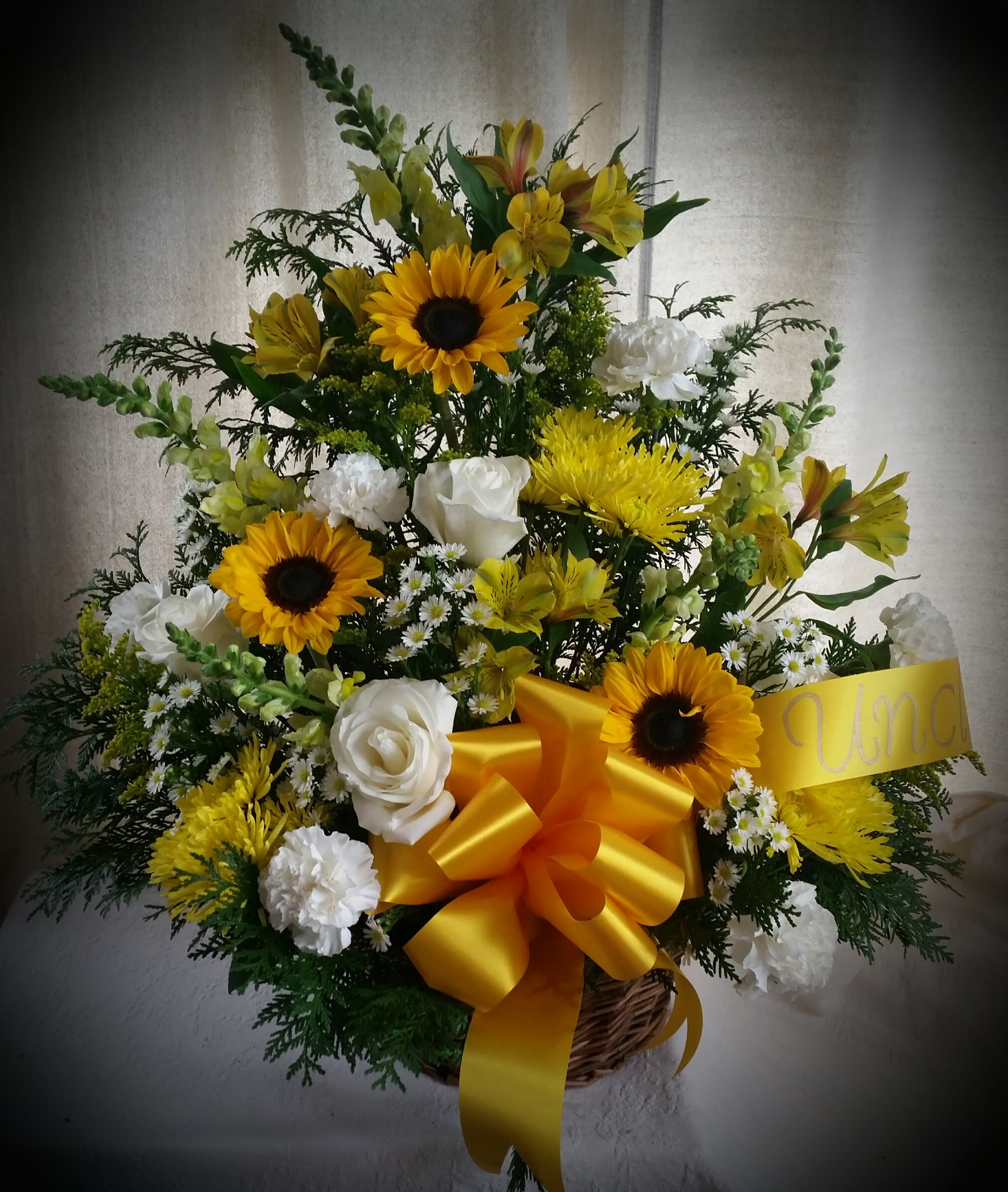 Classic Sympathy Arrangement in Wicker - Snapdragons, sunflowers, roses, carnations, alstroemeria, asters, chrysanthemums and coordinating fillers are arranged in a wicker basket.  A ribbon may be added denoting the sender's relationship to the deceased.