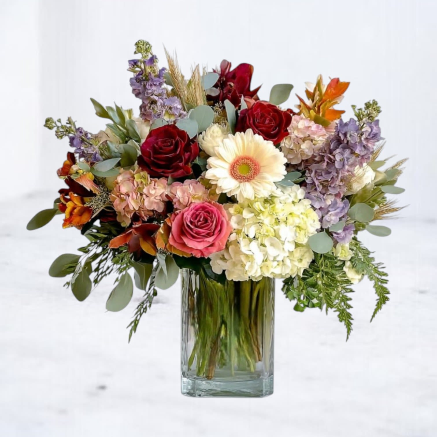 Sweet Meadow Bouquet - The Sweet Meadow Bouquet is a lush celebration of autumn’s natural beauty, blending rich jewel tones with soft seasonal pastels. Featuring burgundy and pink roses, creamy gerbera daisy, lush hydrangea, lavender stock, and accents of seasonal foliage, this arrangement is artfully designed in a tall glass vase. Its balance of warmth and elegance makes it the perfect gift for birthdays, or as a welcoming centerpiece.  Available for same-day flower delivery in Galveston, Houston, and surrounding areas  Substitution Disclaimer: Due to seasonal availability, some blooms may be replaced with similar varieties of equal or greater value to maintain the design’s look and integrity. Your arrangement will always reflect the same spirit, palette, and premium quality.