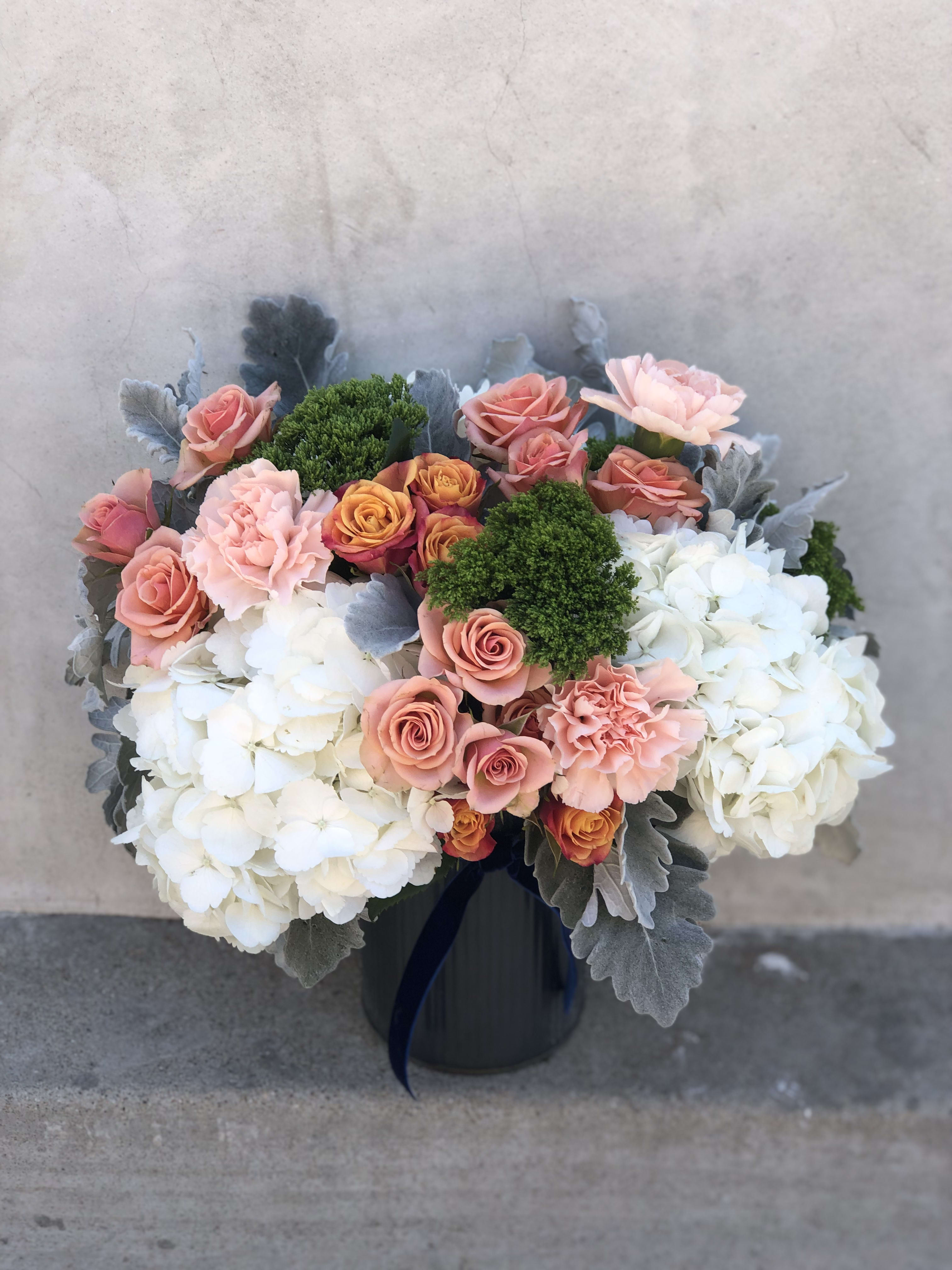 Good Good Vibrations - Giving off good vibrations + excitations, this arrangement is full of lush hydrangeas, citrus hued spray roses, peach carnations, mossy dianthus, silver dusty miller leaves + designed in a galvanized vase accented with velvet ribbon.