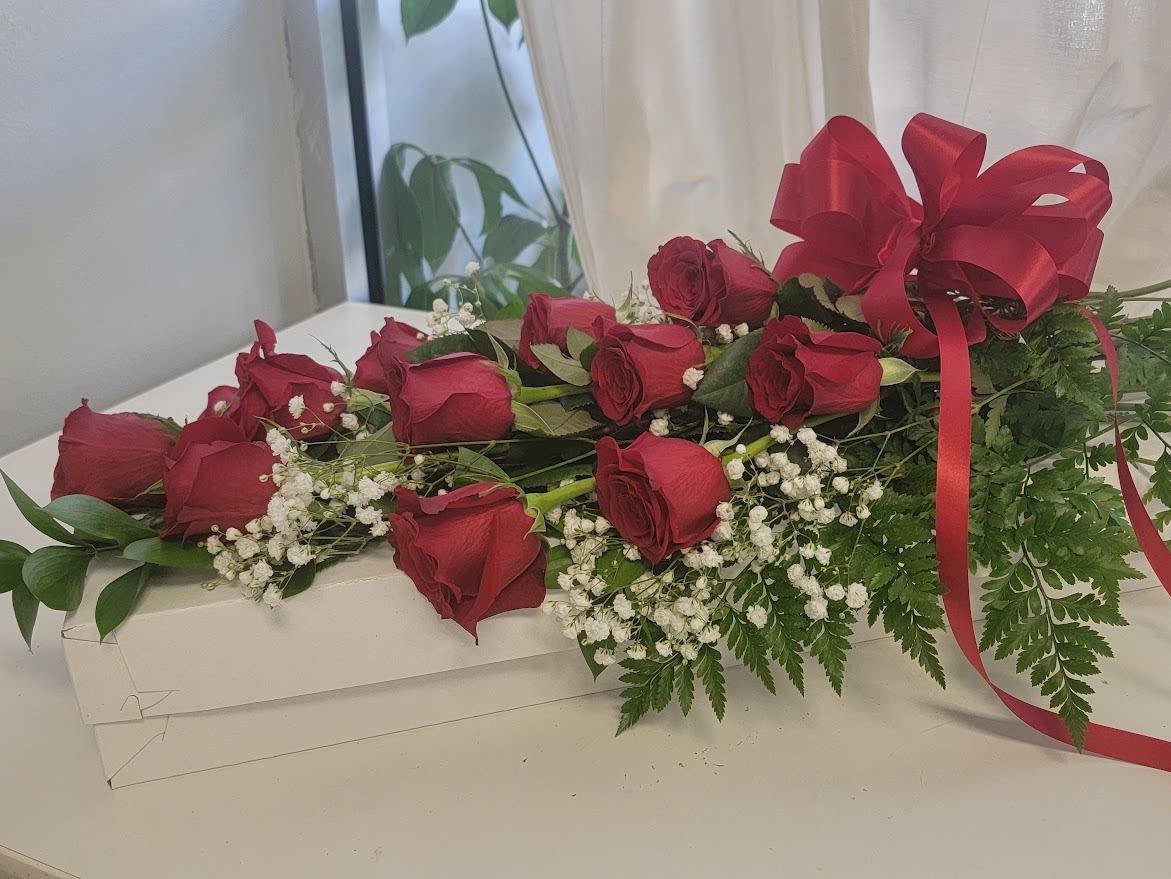 12 Lovely Long Stem Red Roses Boxed - Classic 12 Long Stem Red Roses arranged in a white gift box, includes babies breath and mixed greenery. The gift box is wrapped in a bow. 