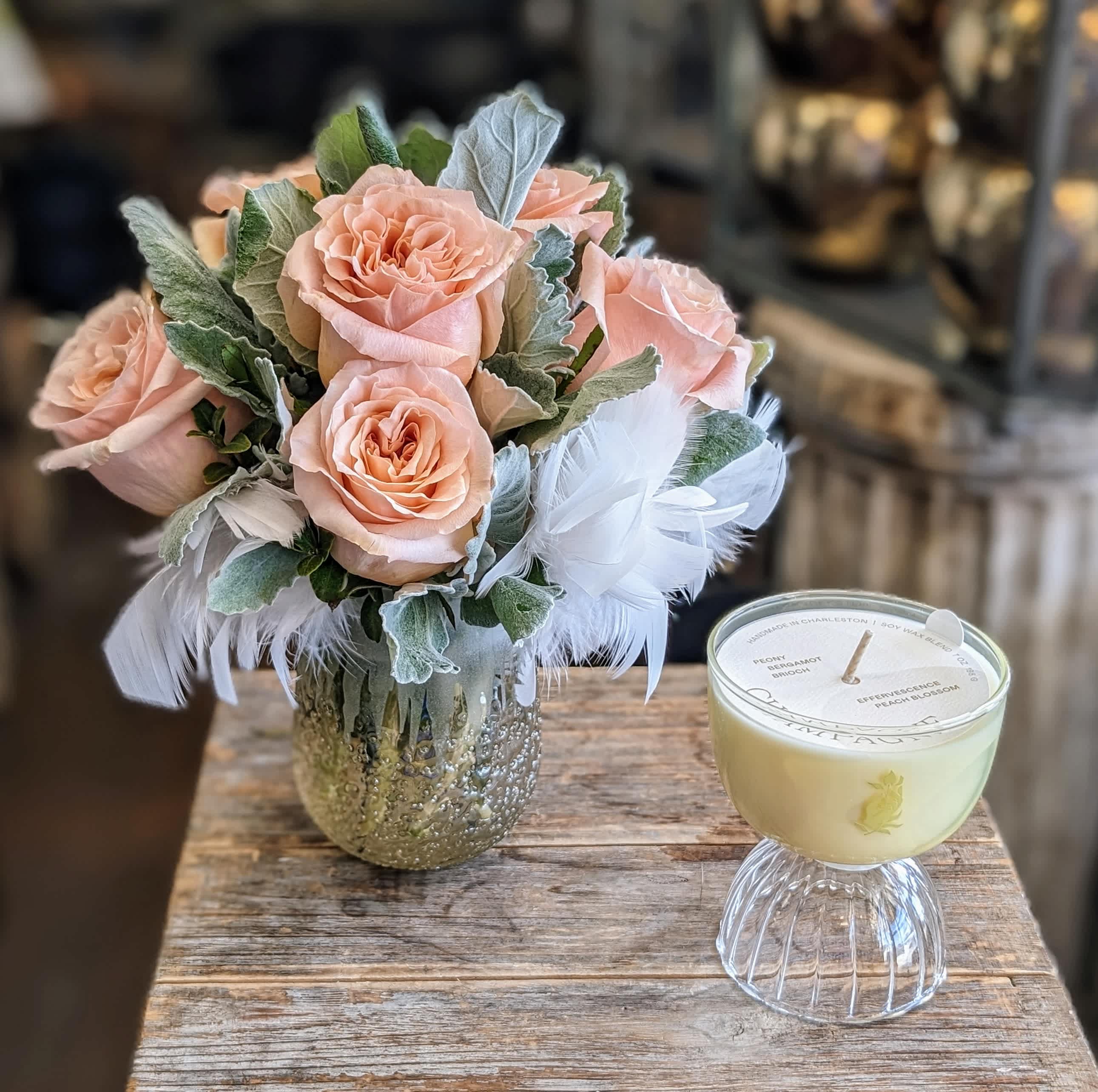 Bubbly - Bubbly by Windmill Floral Expressions in Las Vegas is a toast to joy, elegance, and everyday celebrations. This charming gift set pairs a petite arrangement of nine peach roses with a touch of airy romance—gathered in a textured pale peach vase and accented with fluffy white feathers for a whimsical, effervescent feel.  Accompanying the blooms is a Rewined Coupe Champagne Candle (7 oz)—a hand-poured treasure in an elegant coupe glass, infused with delicate notes of peony, bergamot, and peach blossom. The fragrance captures the sparkle and sophistication of champagne itself, evoking the feeling of raised glasses and unforgettable moments.  Once the candle has burned, the coupe becomes a reusable glass, ready to cradle your favorite bubbly in style.  Whether you're celebrating a birthday, engagement, bridal moment, or simply gifting a little everyday luxury, Bubbly is a radiant reminder that the small things are worth celebrating.  Available for same-day flower and gift delivery in Las Vegas and Henderson.