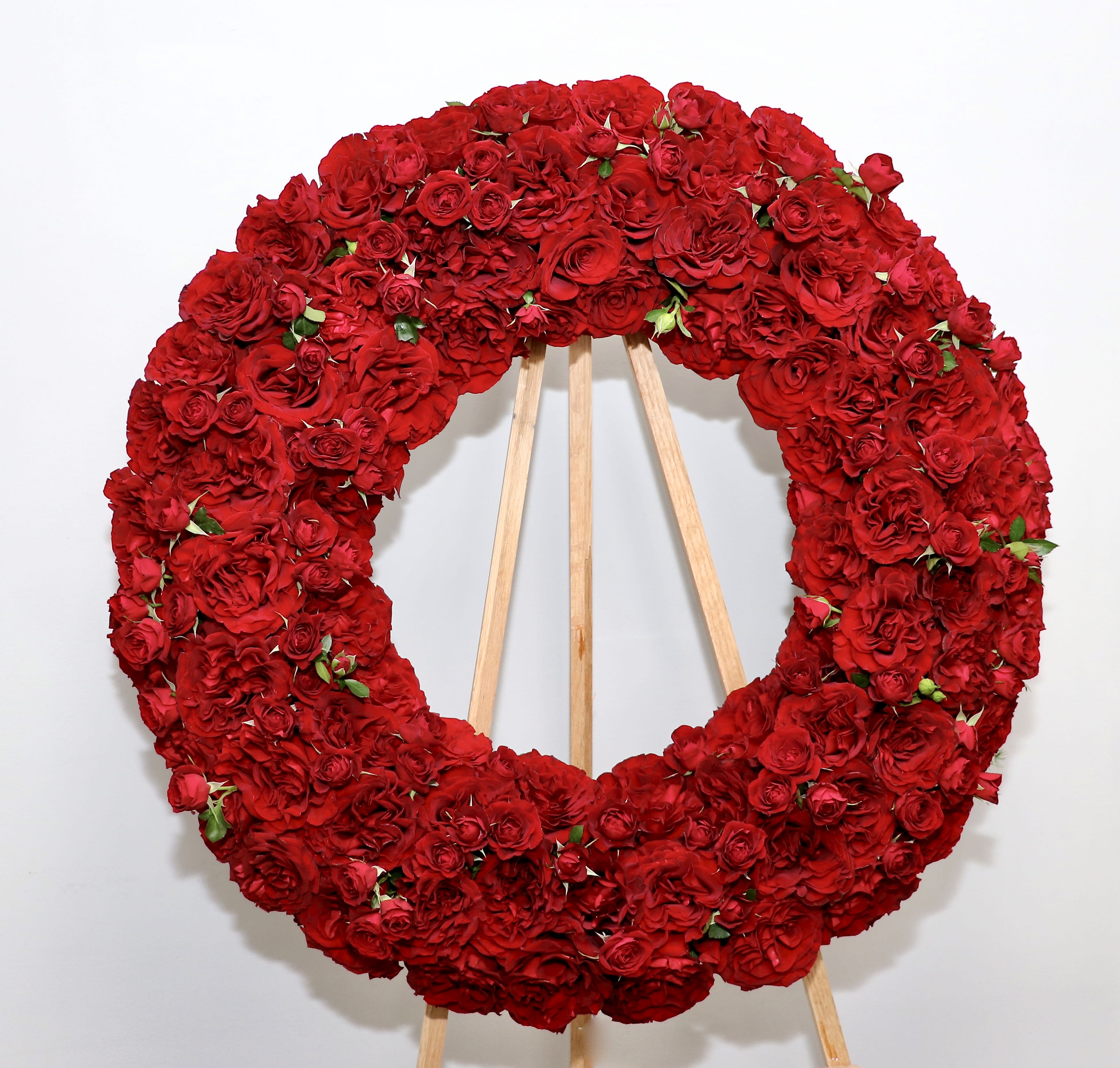 Red Rose Wonder Wreath - This wreath includes premium Ecuadorian red roses.    We include easel, printed banner and delivery (some fees may apply). An additional banner can be added for $15    Standard size is 30'', deluxe is 36'', and premium is 42''.
