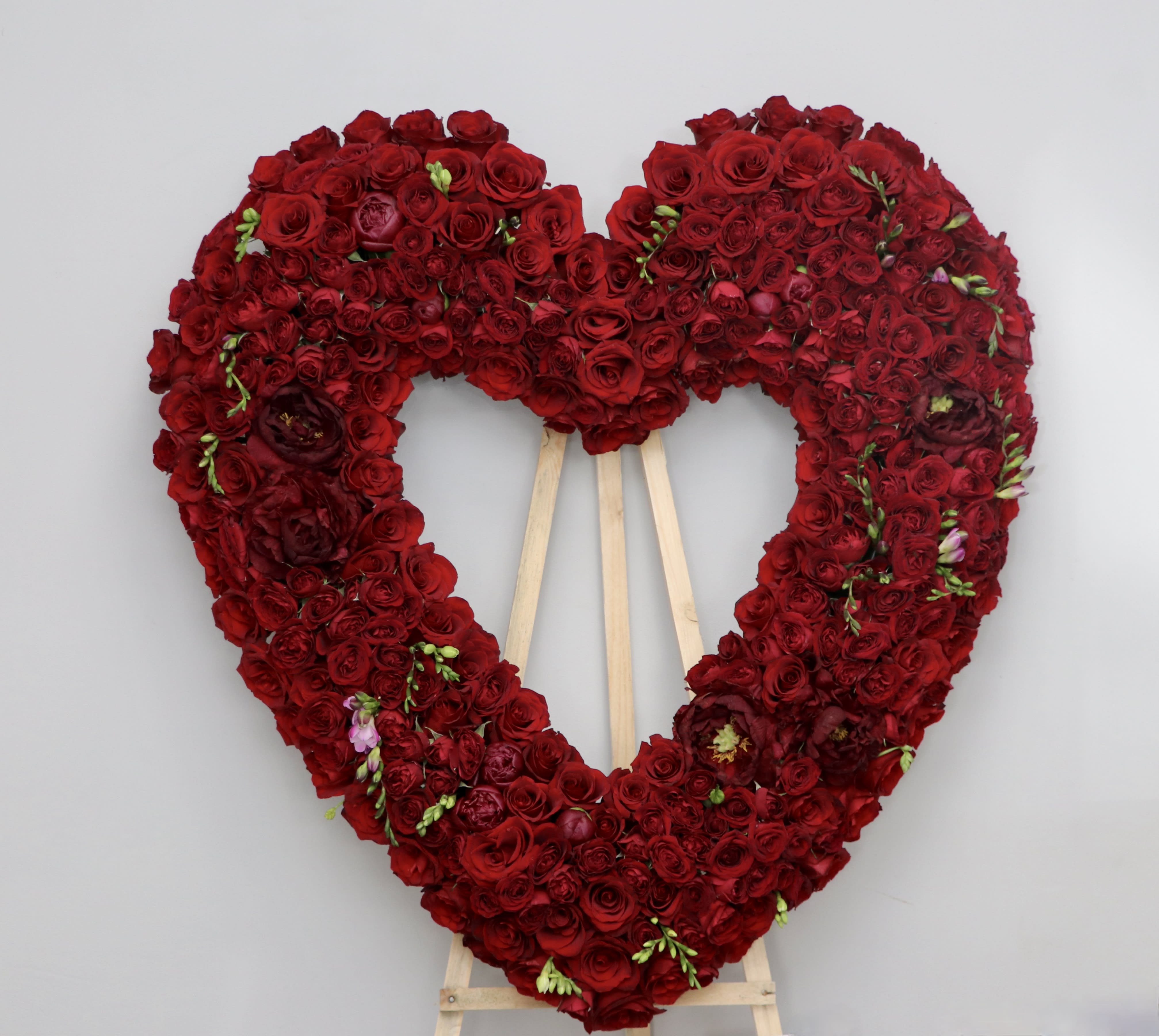 Red Sympathy Heart  - This sympathy heart made with all red roses and florals.  (Photo shows PREMIUM upgrade)    We include easel, printed banner and delivery (some fees may apply). An additional banner can be added for $15    Standard size is 30'', deluxe is 36'', and premium is 42''.    
