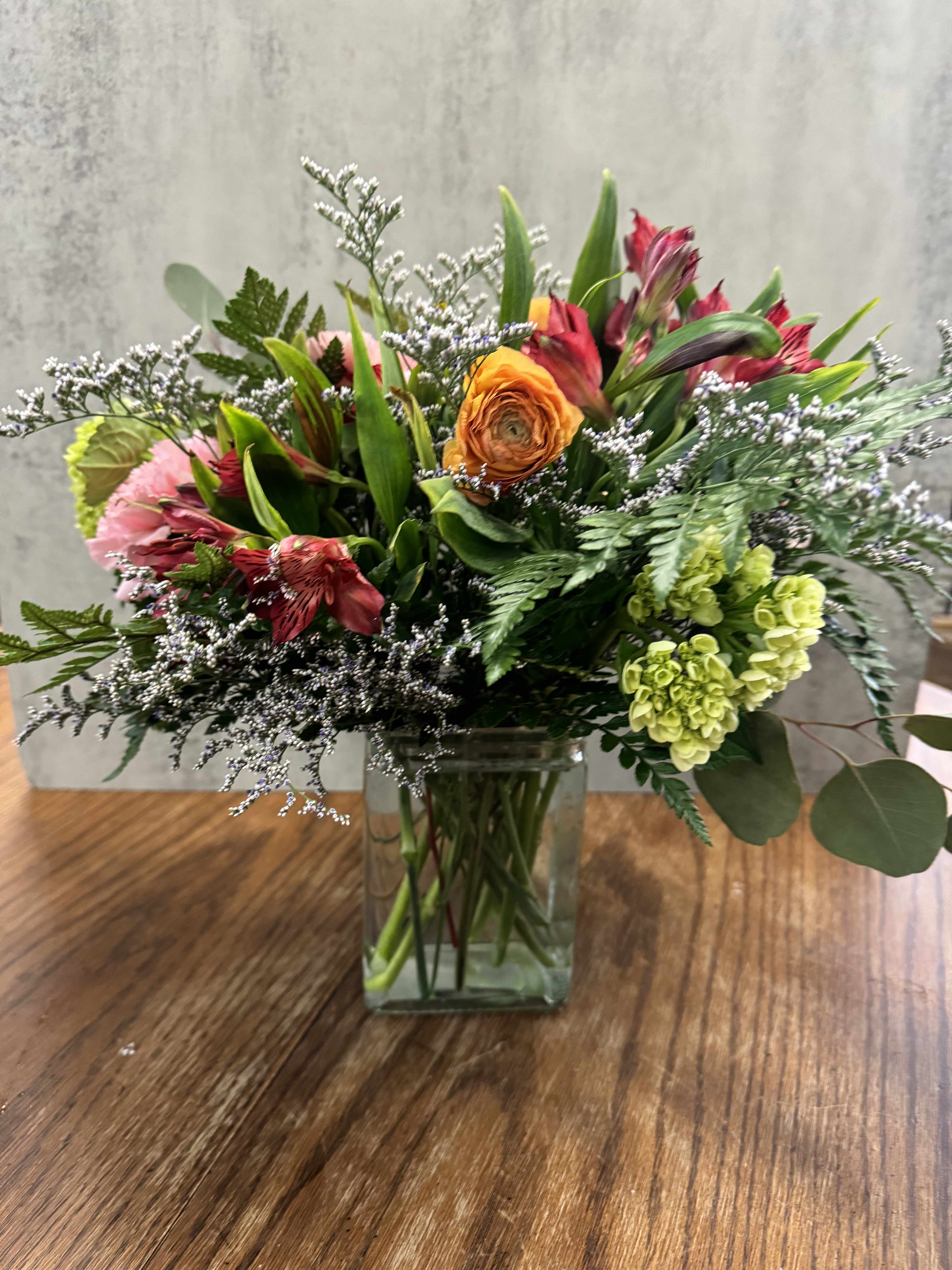 Enchanted Meadow - Step into a serene meadow with our "Enchanted Meadow" arrangement, a lush collection of nature’s finest blooms. This bouquet combines vibrant alstroemeria, playful pinks, rich purples, and refreshing greens, nestled amongst soft white accents, to capture the untamed beauty of a wildflower field. Housed in a sleek glass vase, it brings a touch of the outdoors in, perfect for adding a dash of color and charm to any space.