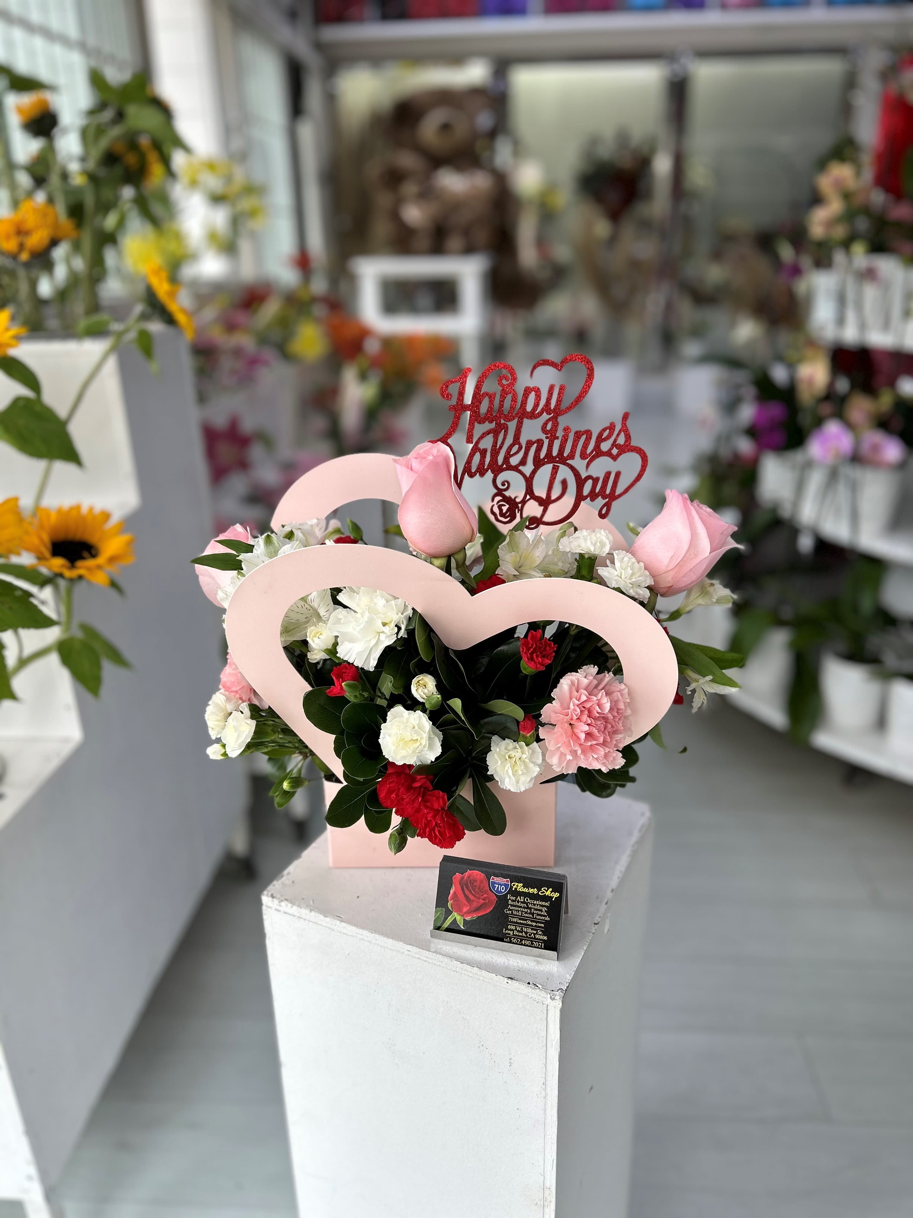 Pink Heart Box Arrangement - A cute pink heart box arrangement with beautiful flowers! Comes included with valentines day sign! Heart Box comes in Pink, Black, and White with a mixture of flowers. If you'd like a specific color please leave note in instructions! (Chose your choice of color. If we do not have the chosen color available or the same flower as photo we will add substitute for next available)