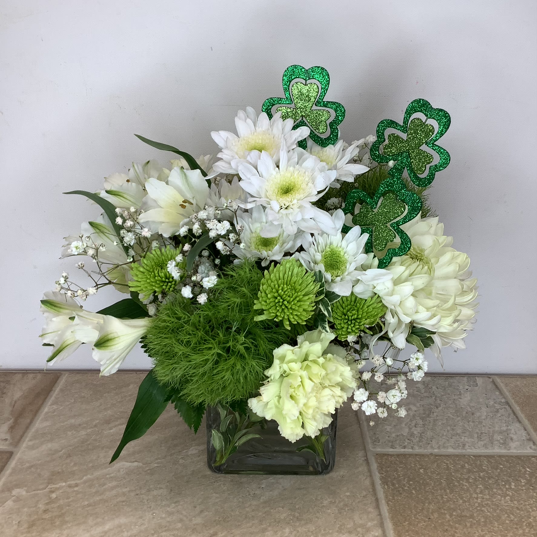 Irish Blessings - A lovely way to celebrate St. Patrick’s Day. Irish Blessings is filled with white cushion mums, Cremona flowers, alstroemeria, baby’s breath and glittered shamrocks.