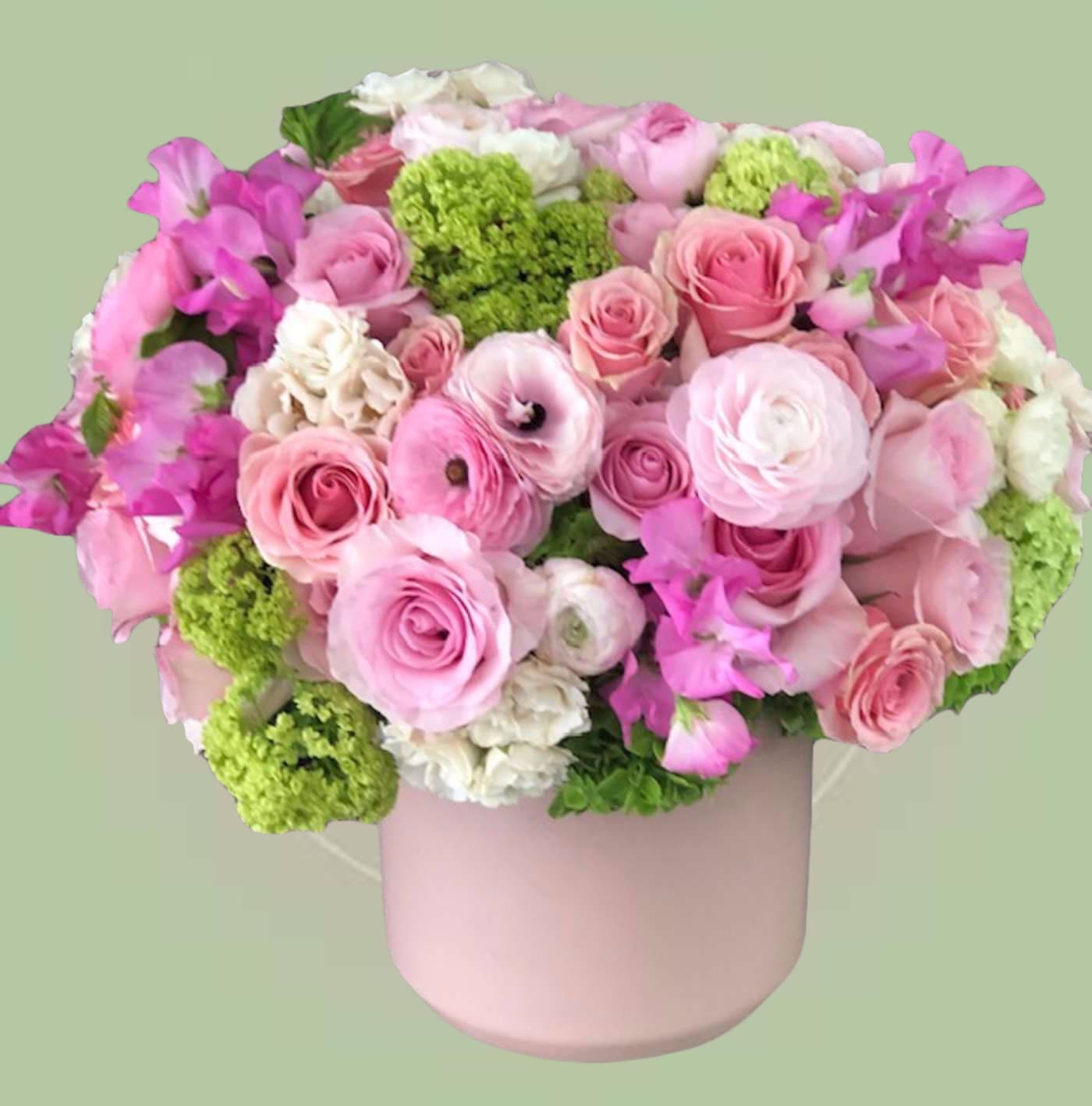 Pink Mixed Flower Box - This lush pink flower box arrangement features premium pink roses, delicate ranunculus, soft sweet peas, and vibrant green viburnum beautifully arranged in a modern blush hat box. Designed in a full, rounded garden style, this mixed floral box offers layers of texture, soft pastel tones, and fresh greenery for a romantic, elegant look.  Perfect for birthdays, anniversaries, Mother’s Day, or special celebrations, this pink flowers in box gift makes a stunning statement and arrives beautifully presented and ready to impress.    