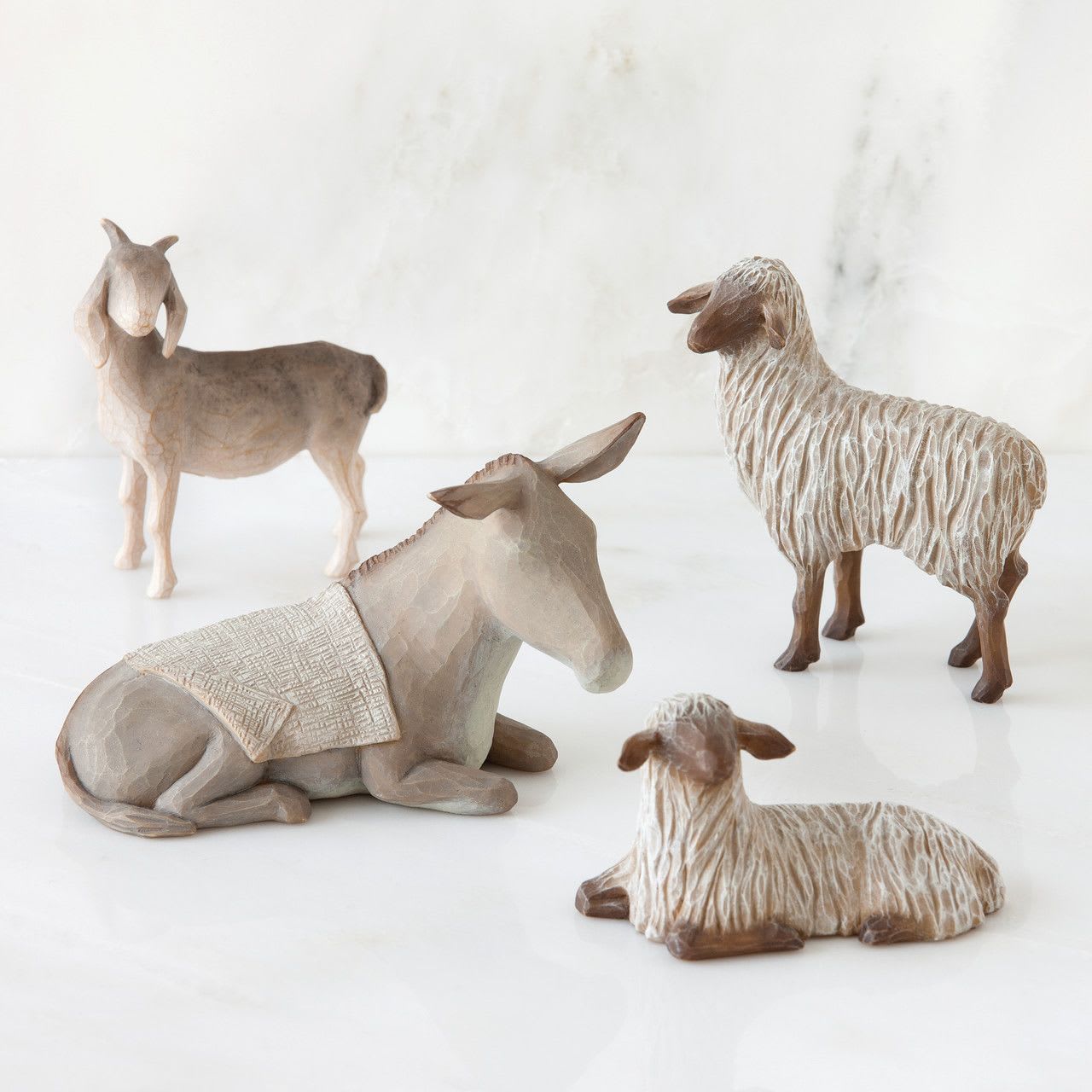 Willow tree - Sheltering Animals for the Holy Family (4 pcs) - Created for Willow Tree® The Holy Family collection. Four animals, tallest is 3”h. Includes donkey, goat and two sheep Gray-white standing goat; gray donkey, lying down with cream-colored blanket on back; two white sheep: one lying down, one standing, with dark face and feet. Sized to complement The Holy Family nativity set Dust with soft cloth or soft brush. Avoid water or cleaning solvents