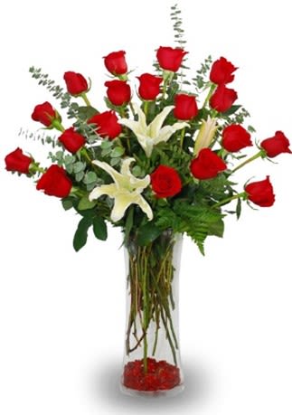 Hearts Desired - "Similiar to our ""True Elegance"" floral arrangement, ""Deeply Desired"" shares the depths of your devotion with the elegant design of red roses nestled with white lilies. Perfect for giving as a gift to a significant other, birthday for her, anniversary, or for a wedding.  Included are 18 long stem red roses and white lilies, supported by traditional tender greens in a pristine clear X-vase."