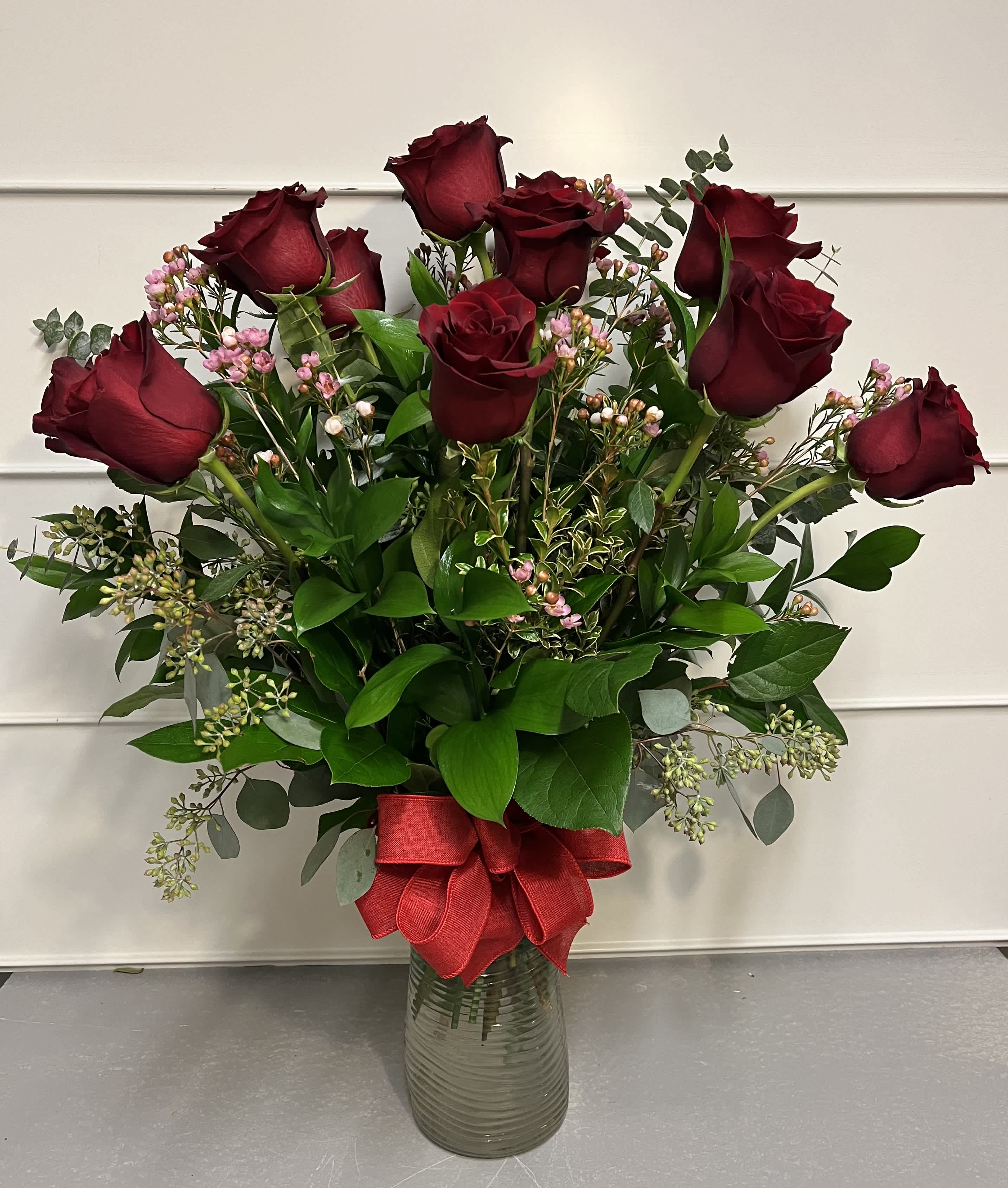 True Love - This arrangement features a dozen, long-stemmed red roses in a vase, with greens and filler. The vase may vary depending on availability.   