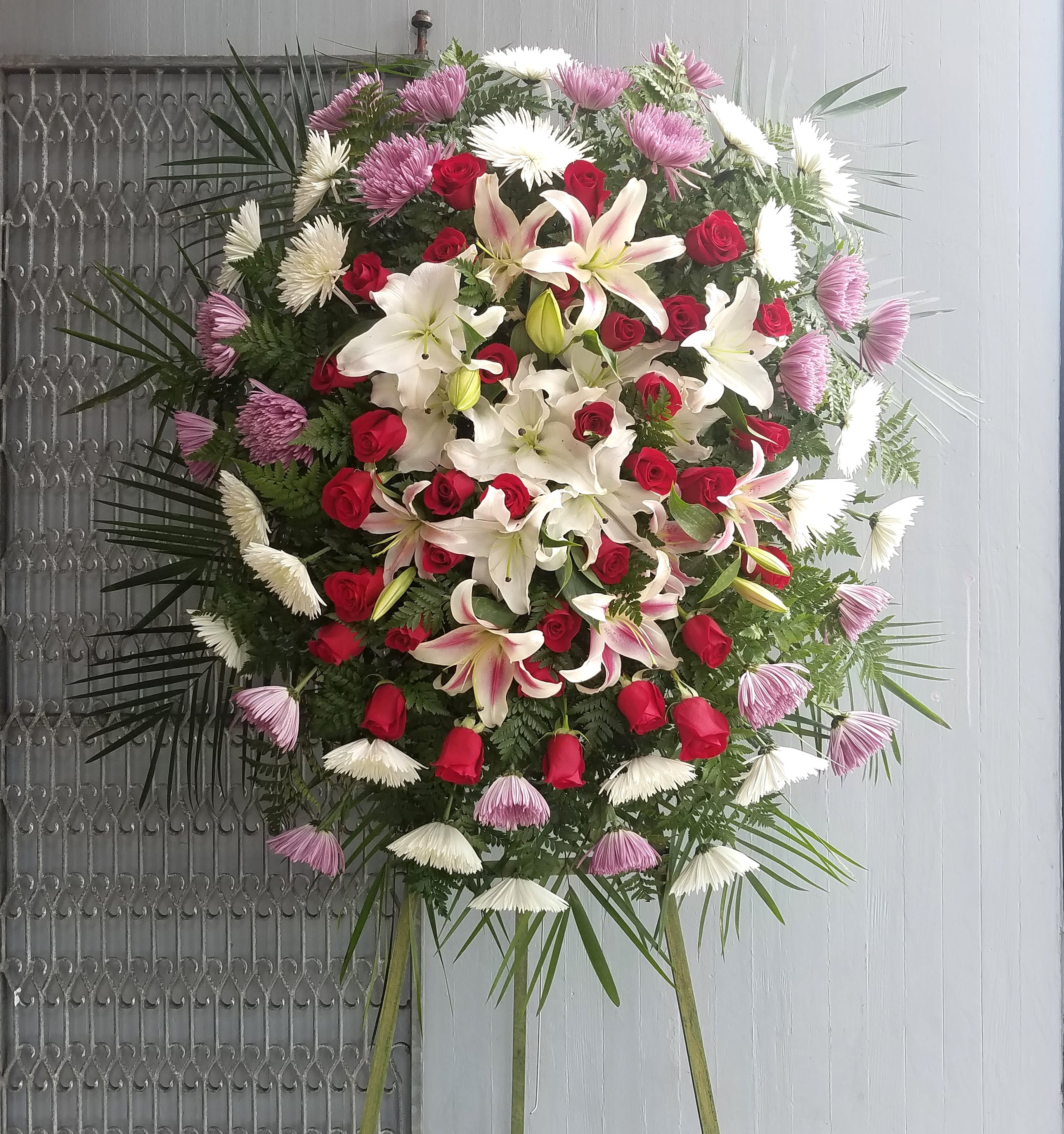 Loving Memories Spray - Loving Memories Standing Spray includes: White Chrysanthemums Purple Chrysanthemums Red Roses White and Pink Lilies  This type of design is usually approximately 5 - 6 ft tall and is meant for funeral services ONLY. This design includes a free banner (please include a banner sign in the Special Instruction Box or Message Box with the title “BANNER”).  In the event a banner space is left blank for any reason, ONLY a card message will be included. Banners are printed in a black 2.5-inch wide ribbon with silver ink. Currently, we don't offer any other colors. If the service is the same day as the order was placed we cannot guarantee delivery by a certain time. And flowers will be delivered during normal business hours.  To ensure the delivered flowers match the displayed photo as close as possible we recommend ordering 3-5 days in advance. For the same or next day deliveries, we reserve a right to substitute flowers with the same or greater value.