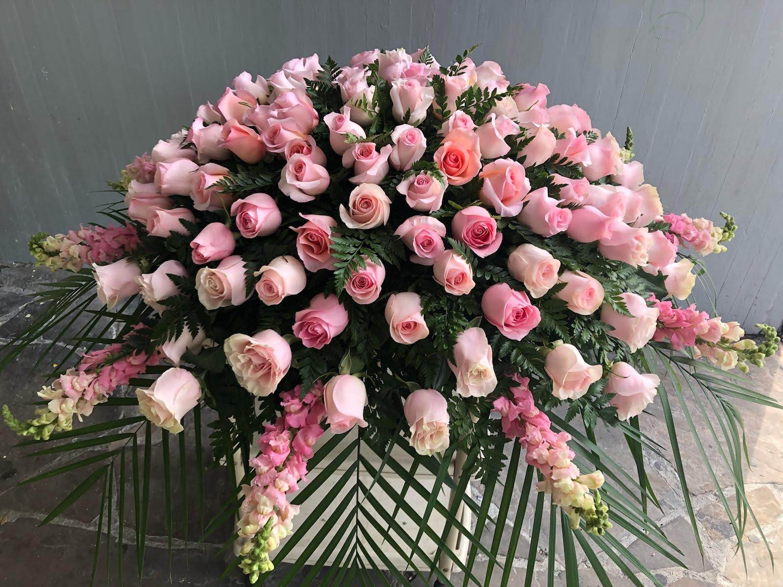 Peaceful Light Casket Spray - Peaceful Light Casket Spray includes: Pink Roses Pink Snapdragons  Colors can be substituted upon availability.   This type of design usually measures approximately 5 ft x 3 ft x 1ft and is meant for funeral services ONLY. This design includes a free banner (please include a banner sign in the Special Instruction Box or Message Box with the title “BANNER”).  In the event a banner space is left blank for any reason, ONLY a card message will be included. Banners are printed in a black 2.5-inch wide ribbon with silver ink. Currently, we don't offer any other colors. If the service is the same day as the order was placed we cannot guarantee delivery by a certain time. And flowers will be delivered during normal business hours.  To ensure the delivered flowers match the displayed photo as close as possible we recommend ordering 3-5 days in advance. For the same or next day deliveries, we reserve a right to substitute flowers with the same or greater value. Please read our substitution policies below.