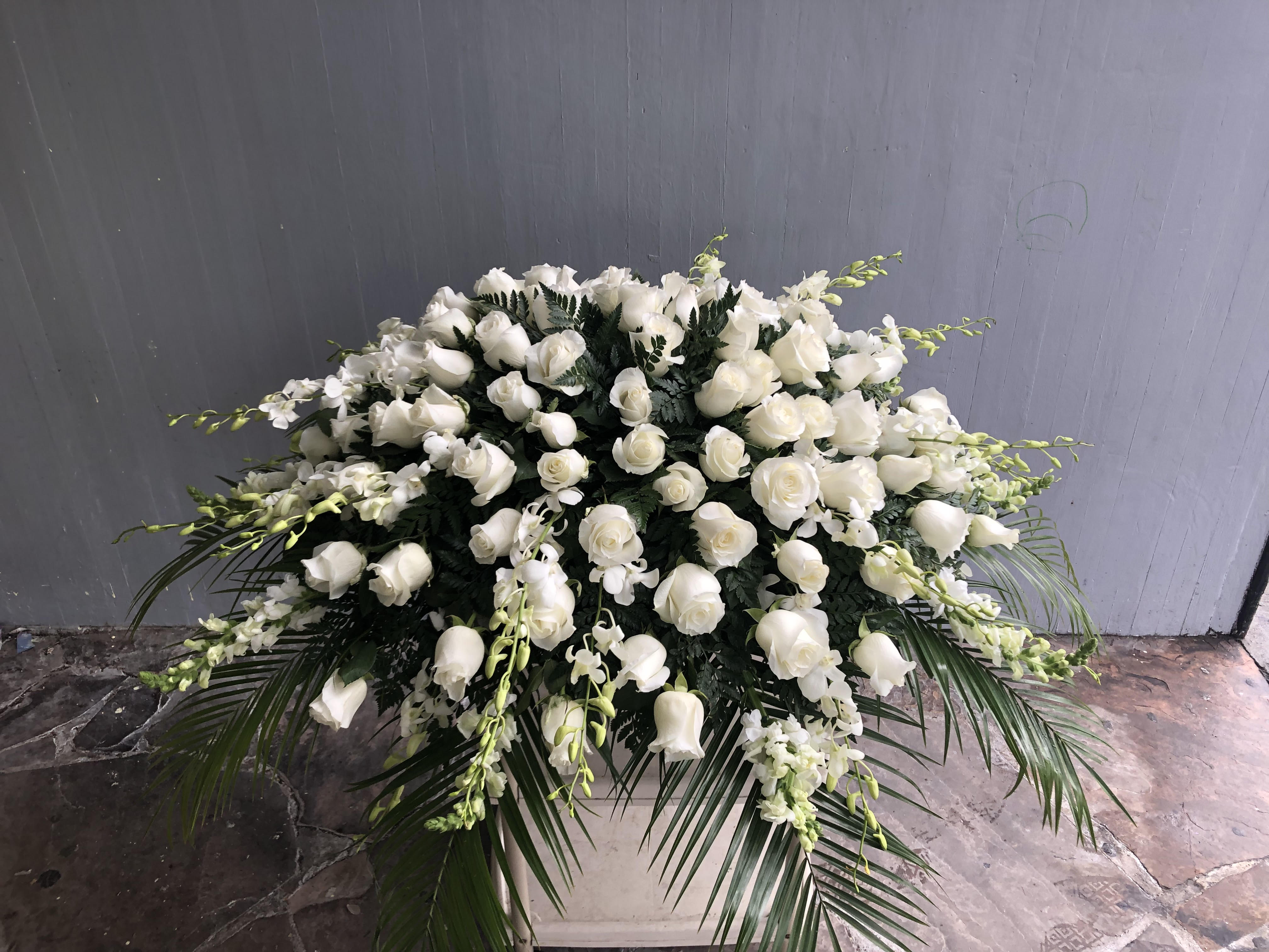 Peace and Hope Casket Spray - Peace and Hope Casket includes:  White Roses White Carnations White Snapdragons White Gladiolus  White Dendrobium Orchids  This type of design usually measures approximately 5 ft x 3 ft x 1ft and is meant for funeral services ONLY. This design includes a free banner (please include a banner sign in the Special Instruction Box or Message Box with the title “BANNER”).  In the event a banner space is left blank for any reason, ONLY a card message will be included. Banners are printed in a black 2.5-inch wide ribbon with silver ink. Currently, we don't offer any other colors. If the service is the same day as the order was placed we cannot guarantee delivery by a certain time. And flowers will be delivered during normal business hours.  To ensure the delivered flowers match the displayed photo as close as possible we recommend ordering 3-5 days in advance. For the same or next day deliveries, we reserve a right to substitute flowers with the same or greater value. Please read our substitution policies below.