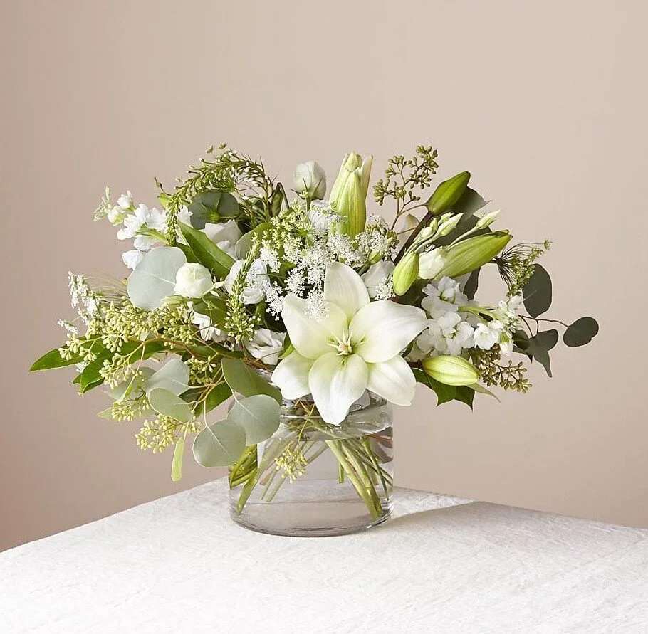 Elegance in White - An all white bouquet of white lilies, white Stock and seeded eucalyptus in cylinder glass vase
