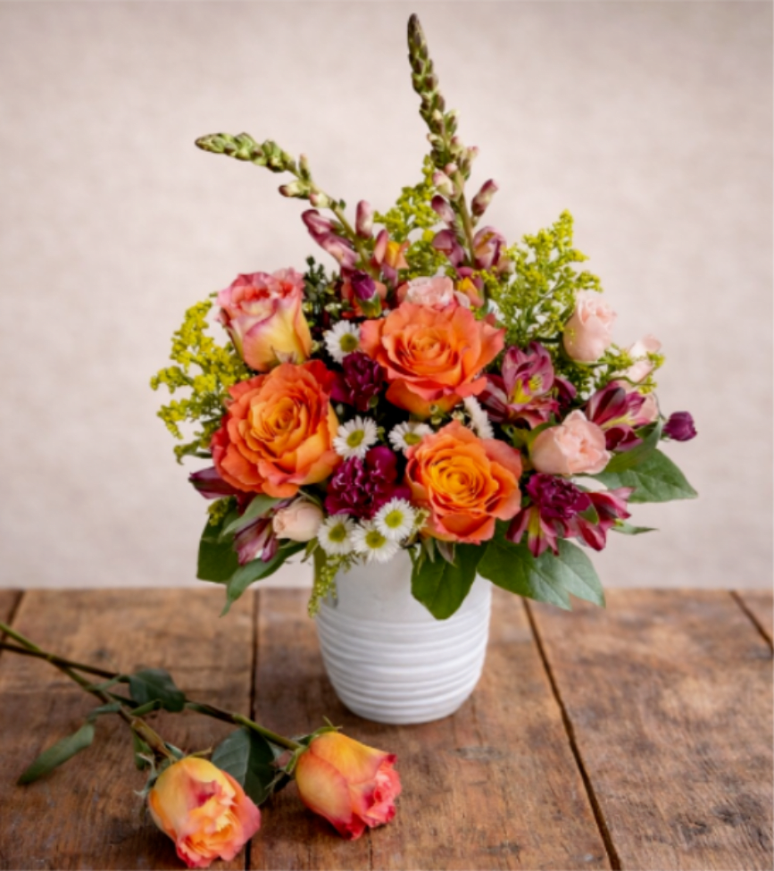 Blooming Blossoms  - Enhance your home decor with our stunning vase filled with a vibrant mix of orange and pink roses. Perfect for adding a pop of color and elegance to any room, these fresh flowers will brighten up your space and create a warm and inviting atmosphere. Ideal for special occasions or as a thoughtful gift for a loved one, this beautiful arrangement is sure to impress.   A unique arrangement of orange roses, snapdragons, and beautiful filler flowers to brighten your special someone's day. Hand-created by our experienced designers. Please note that every design is custom made and substitution to container and flower types may happen from time to time. Design aspects will always stay the same, but if needed, we will substitute with flowers of equal or greater value to offer you a great floral shopping experience! Our flowers are 100% guaranteed. Please call us with any questions or concerns.