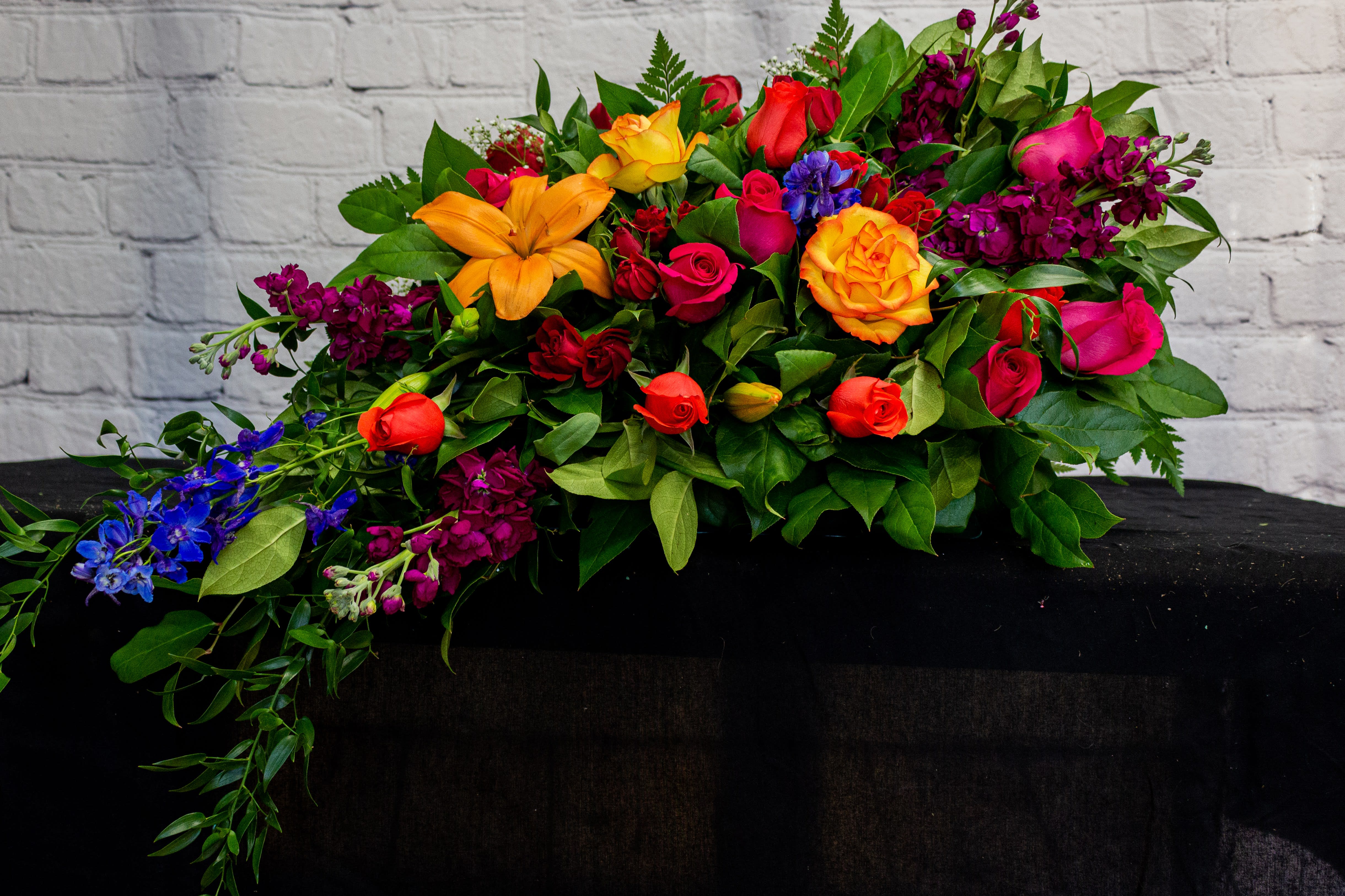 FUNERAL CASKET COVER - Rainbow of Love 100 - This is a stunning option for a funeral service or church. This casket spray is a smaller scale spray that will add a touch of flowers to the top of the casket. This spray can also be made into a half casket spray for an open casket service or a full casket spray for a closed casket service. The piece is a stunning mix of bright colorful flowers will add joy on your day of rememberance.   **This is a piece for a funeral or memorial service. Please place the order at least 2 days prior to the service to guarantee a certain arrangement. Anything sooner and we cannot guarantee it will match the picture. These pieces can be customized to the color of your choice. The flowers may vary depending on availability of the flowers, special requests and quality of the flowers we have in stock. If you have a special request please add it to our special instructions when placing your order. If you have any questions please don’t hesitate to call. 714 289 1123**