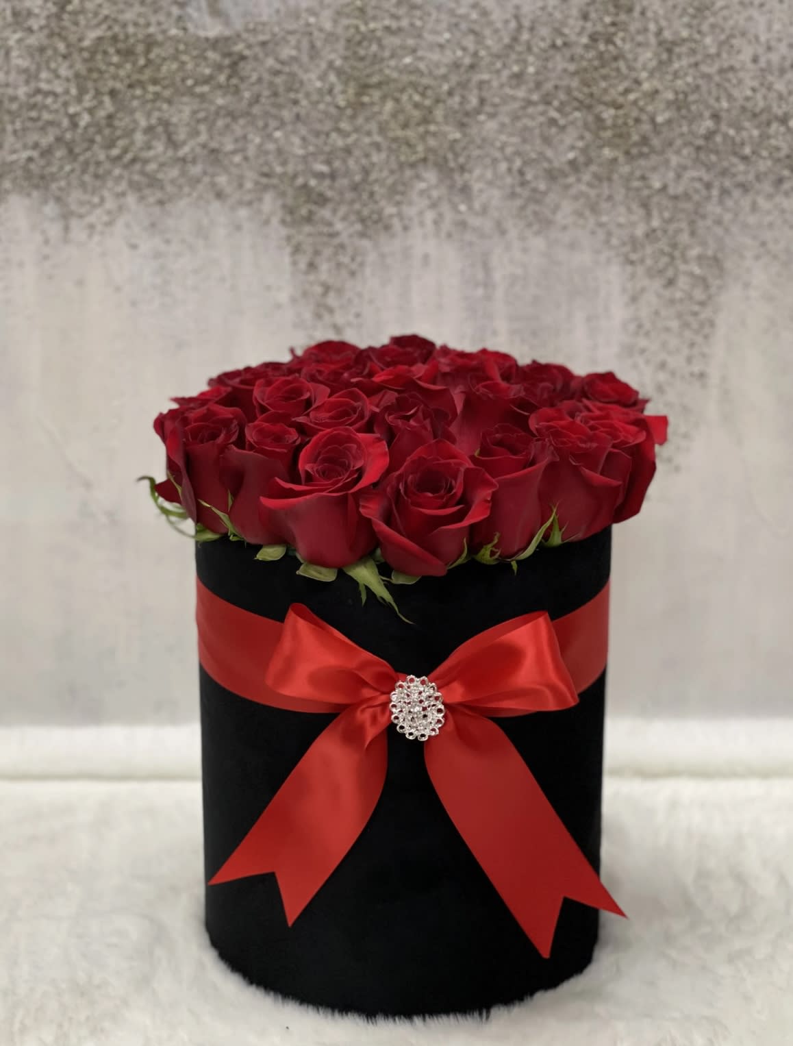 Kickstart My Heart - Beautiful Red roses arranged in a black box, tied with a red ribbon and a pin in the middle.