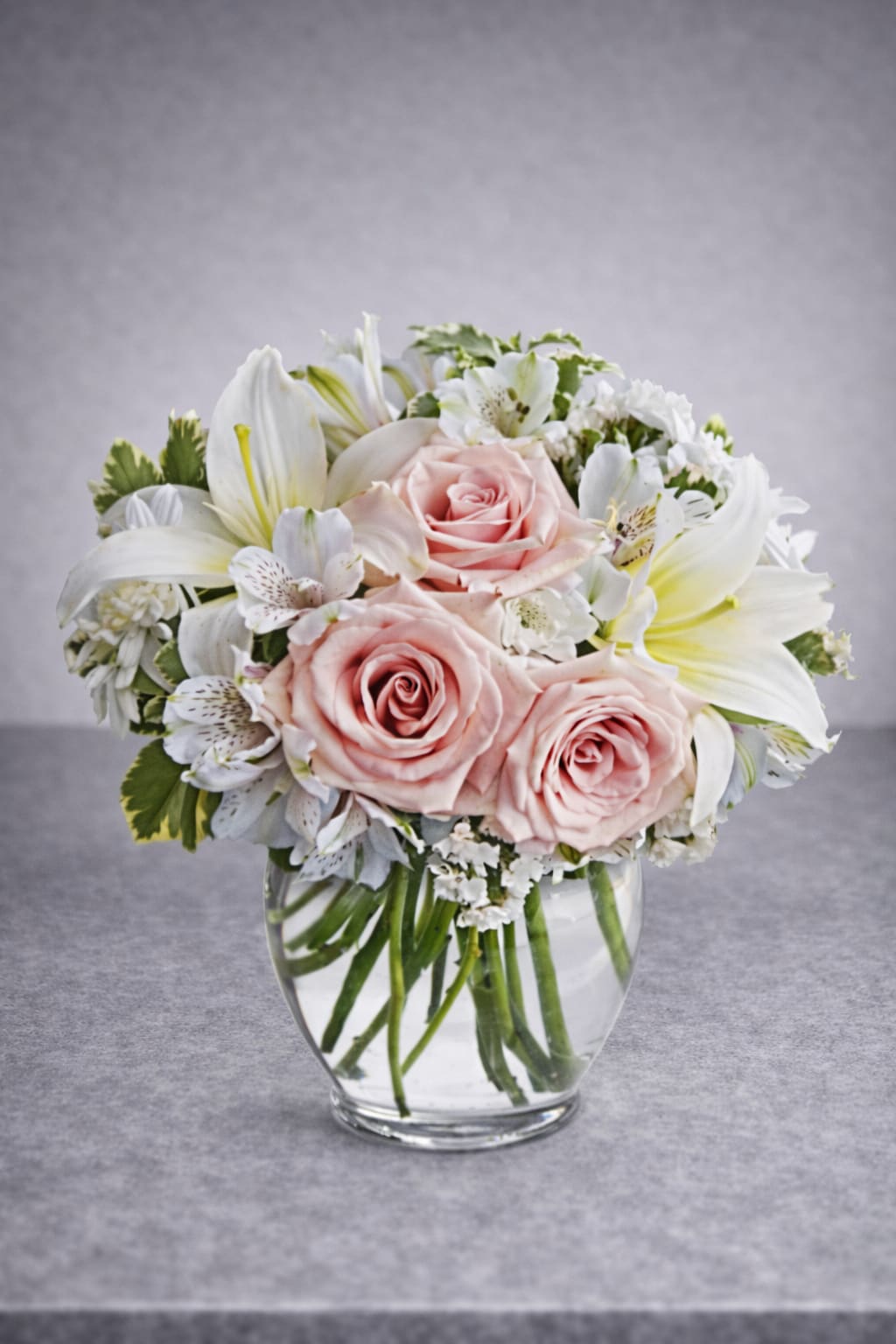 Arrive in Style - When you want your best wishes to arrive in high style, go with this fashionable, feminine bouquet! Full and fragrant, it gathers soft pink roses with white lilies, alstroemeria and mums into a rounded ginger vase.