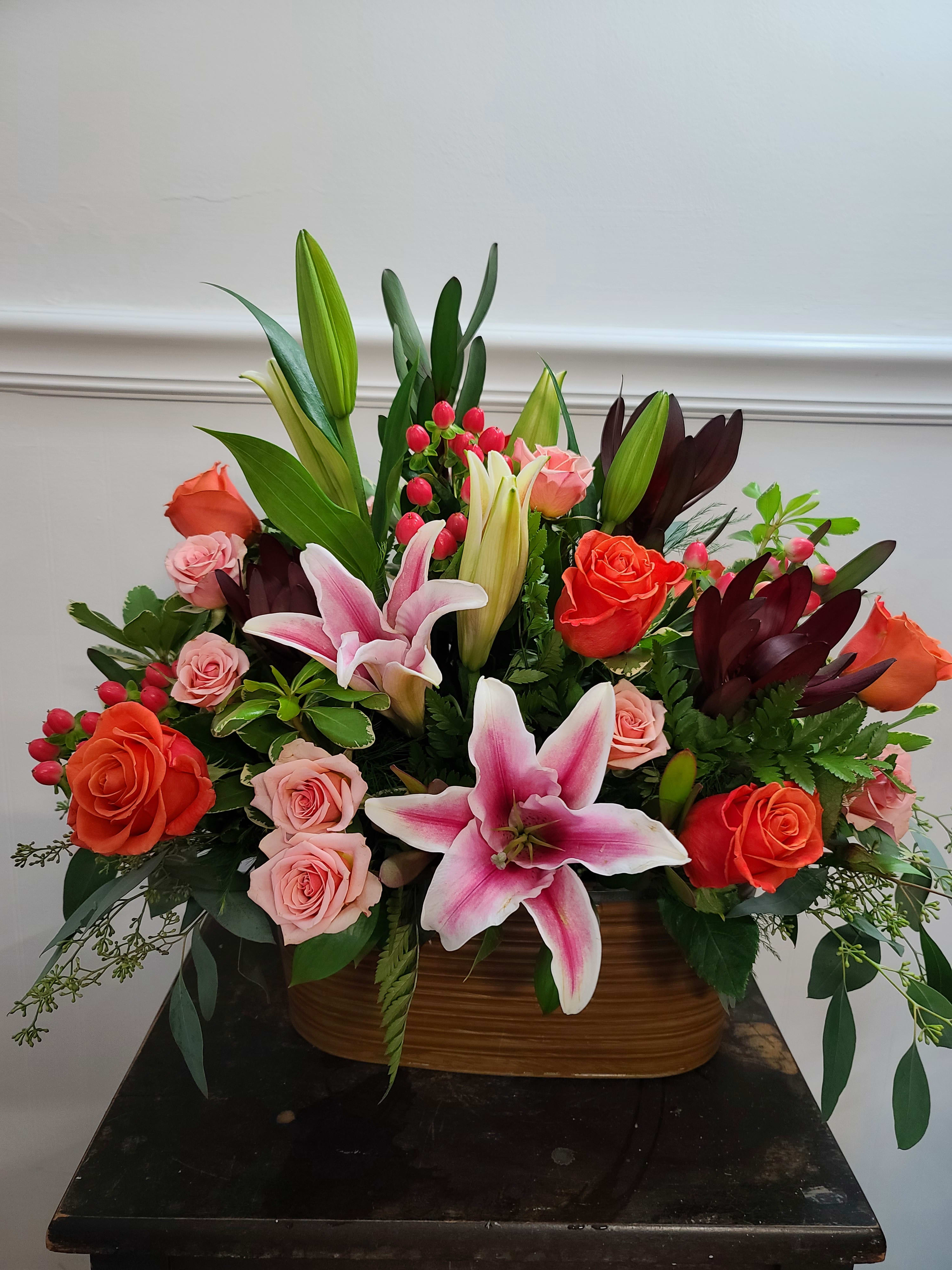 Graceful Sunset - A simple arrangement of Pink Lilies and colorful roses mixed with an assortment of greenery and presented in a rustic container. Perfect for an at-home or business event. An excellent all purpose selection. Exact container may vary. 