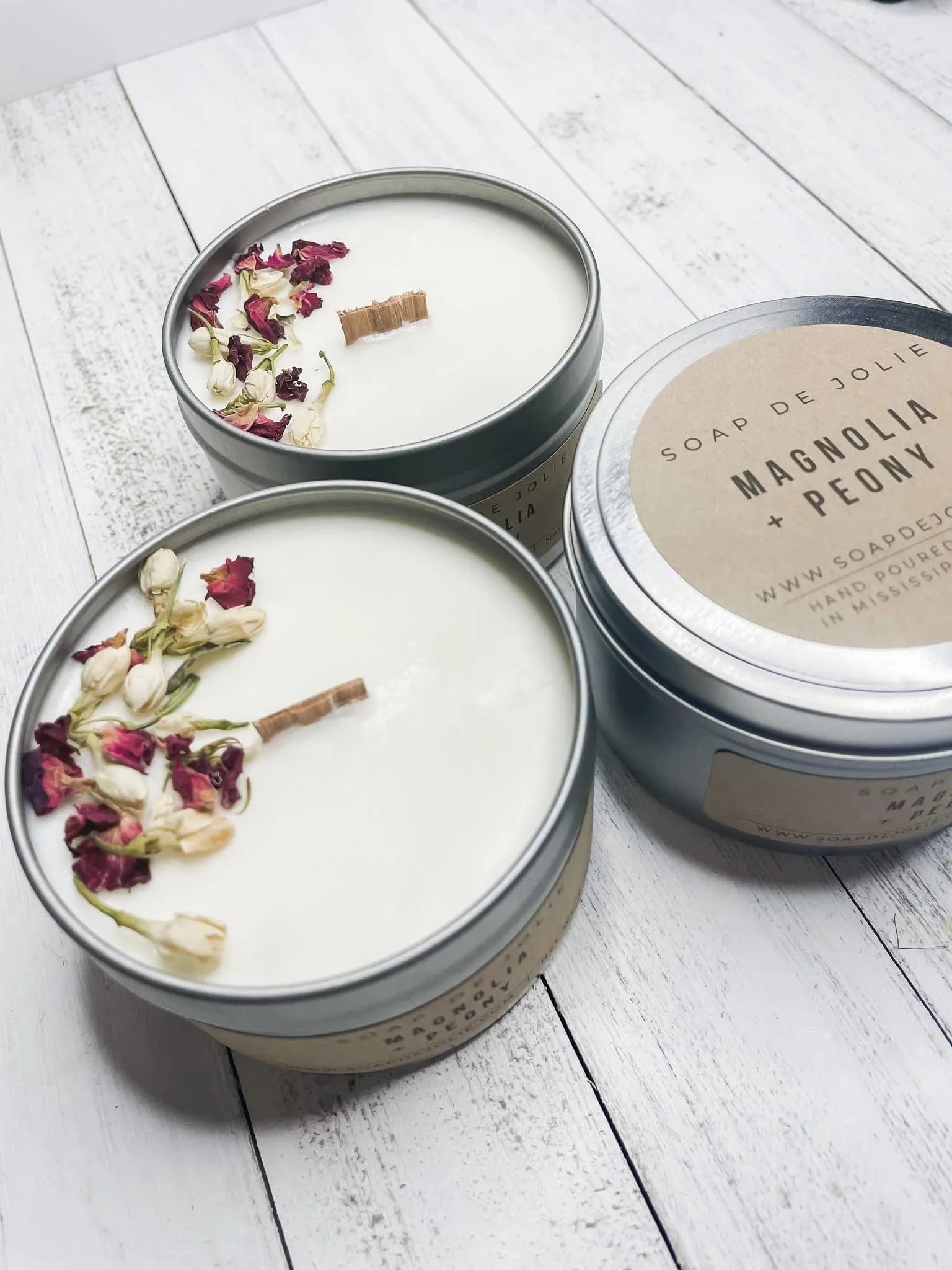 Magnolia &amp; Peony Candle Tin (BR) - Hand poured 8 oz tin candles filled with 6 oz. of soy wax, fitted with a wooden wick. Soy wax is a more pure, longer burning wax, giving each candle a longer burn time while enjoying the soft crackling sound from the wooden wick. Delicate yet satisfyingly bold, this fragrance captures spring at the peak of its blossoming glory with its marriage of magnolia, rose, orange flower, jasmine and lily. Base notes of fresh greens and wood wrap up this complex bouquet with a clean, graceful fragrance. 
