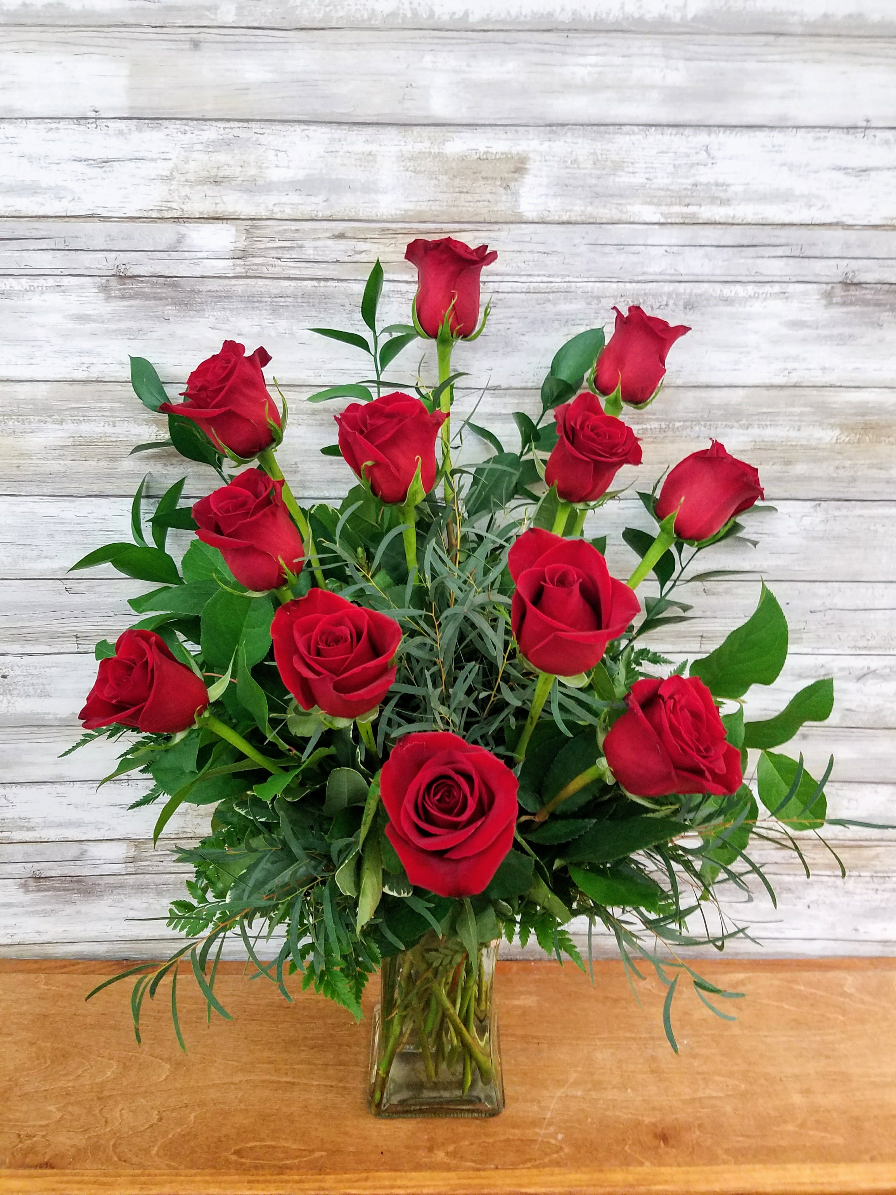 12 Red Premium Long Stem Roses - A Classic Arrangement for Any Occasion.  12 premium long stem red roses arranged with greens in a clear vase. Measures approximately 30" Tall  