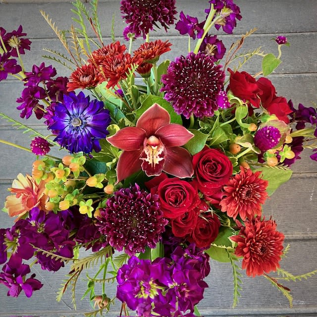 Spellbound - Send a mystical and whimsical floral design with the Spellbound arrangement, perfect for the Autumn season. Featuring flowers such as Cymbidium Orchids, Anemones, and Scabiosa in seasonal fall colors in shades of purples, reds, and multiple neutral hues. This exquisitely magical bouquet brings with it enchanting beauty and makes the perfect gift. 