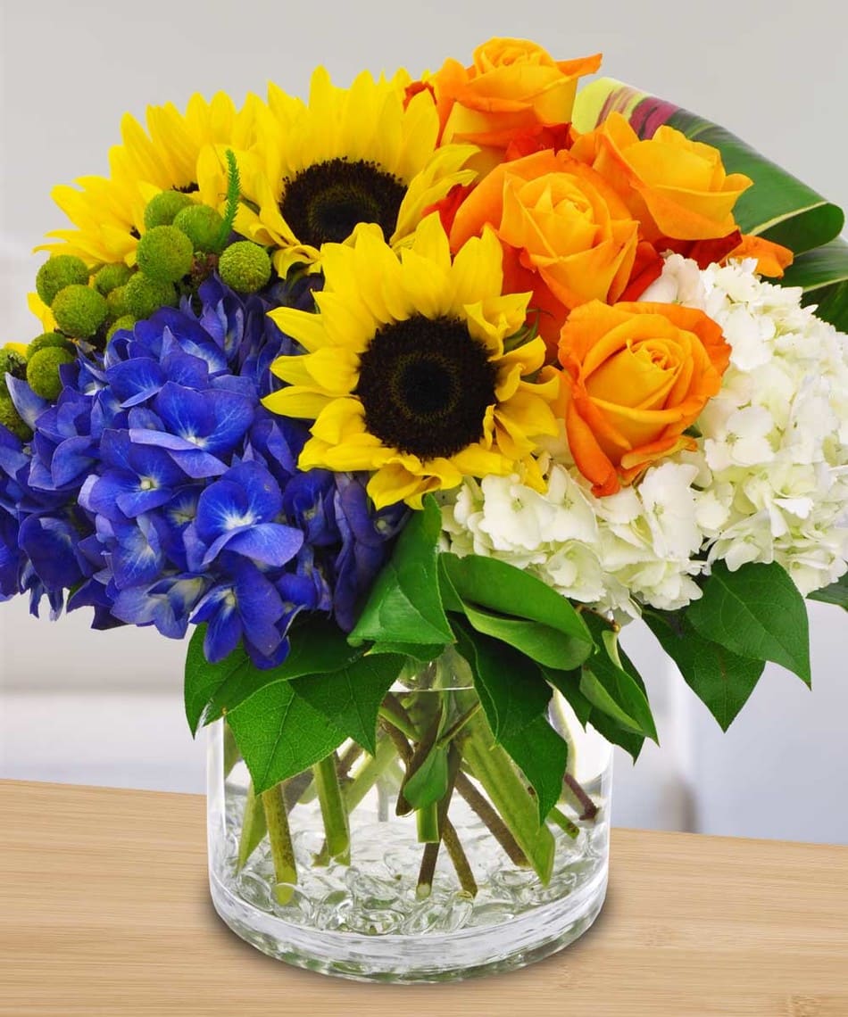 Delightful - A vibrant bouquet featuring sunflowers, roses and hydrangea nestled together to form this beautiful masterpiece.  PLEASE NOTE: Florist reserves the right to make modifications to the design based on seasonality and accessibility of blooms and vases. Any modifications made will honor the palette, intent, and feeling of the pictured design. Contact floral designer directly with any specifications or concerns.