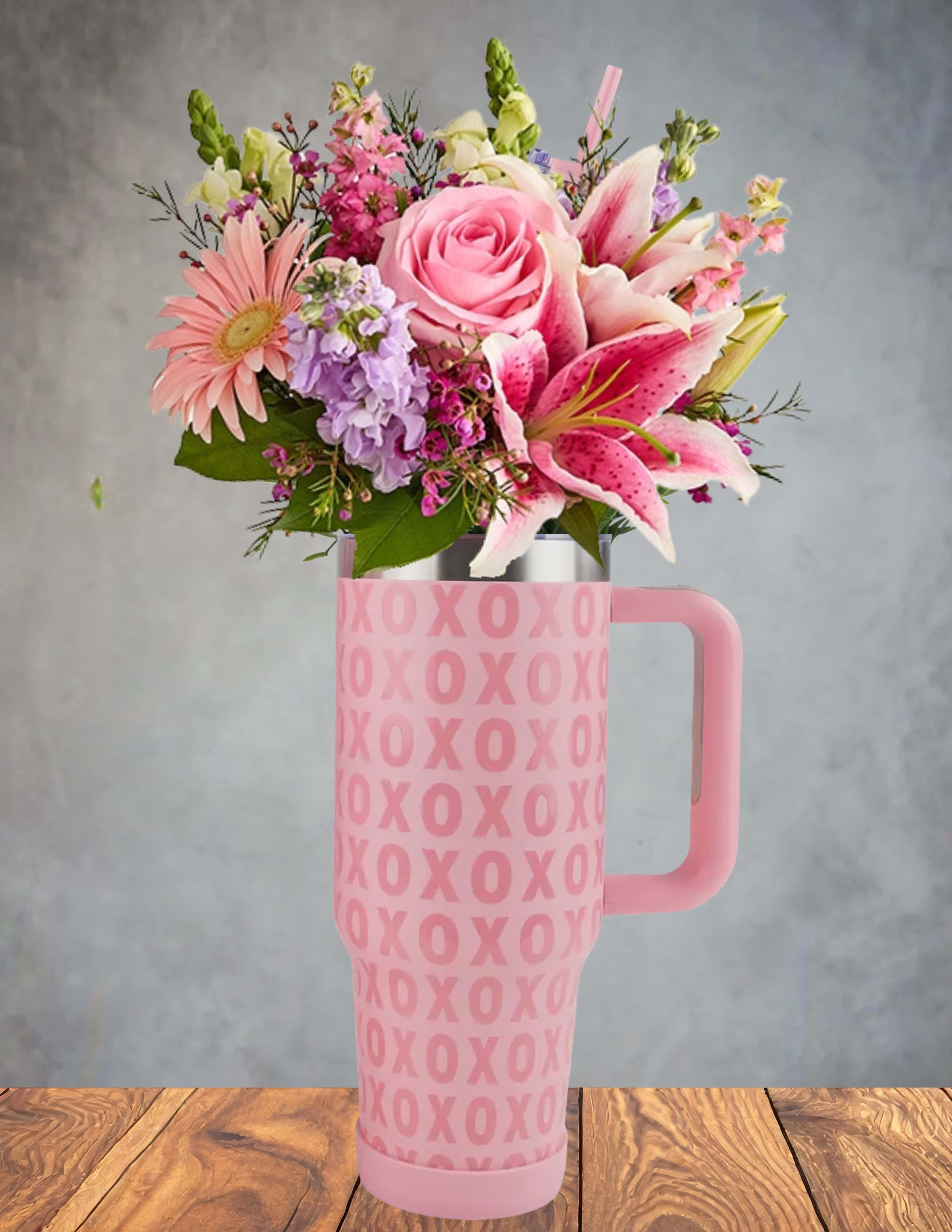 Kiss and Sip -  Kiss and Sip is a playful floral creation nestled inside a pink travel mug adorned with bold "XOXO" lettering. Overflowing with vibrant blooms—roses, lilies, daisies, and snapdragons—it’s a bouquet that speaks the language of love and joy. The mug’s cozy handle invites you to hold onto warmth, while the flowers burst with color and affection. Perfect as a Valentine’s gift, a sweet surprise for a loved one, or a cheerful desk companion, this piece says “I’m thinking of you” with every petal and sip.