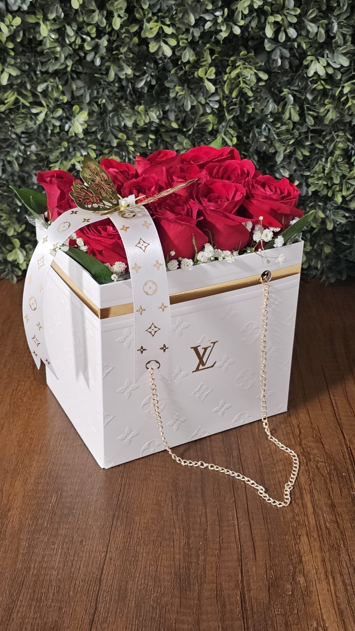 White LV Bag - Vibrant roses, delicate baby's breath, lush greenery, and a gold butterfly accented with a LV ribbon.