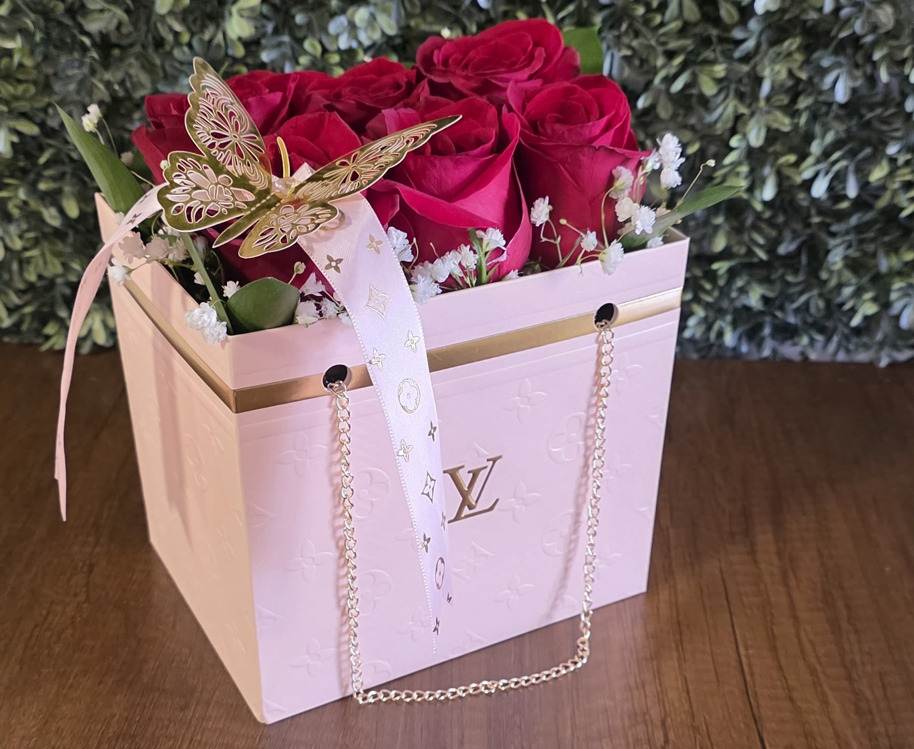 Pink LV Bag - Vibrant roses, delicate baby's breath, lush greenery, and a gold butterfly accented with a LV ribbon.