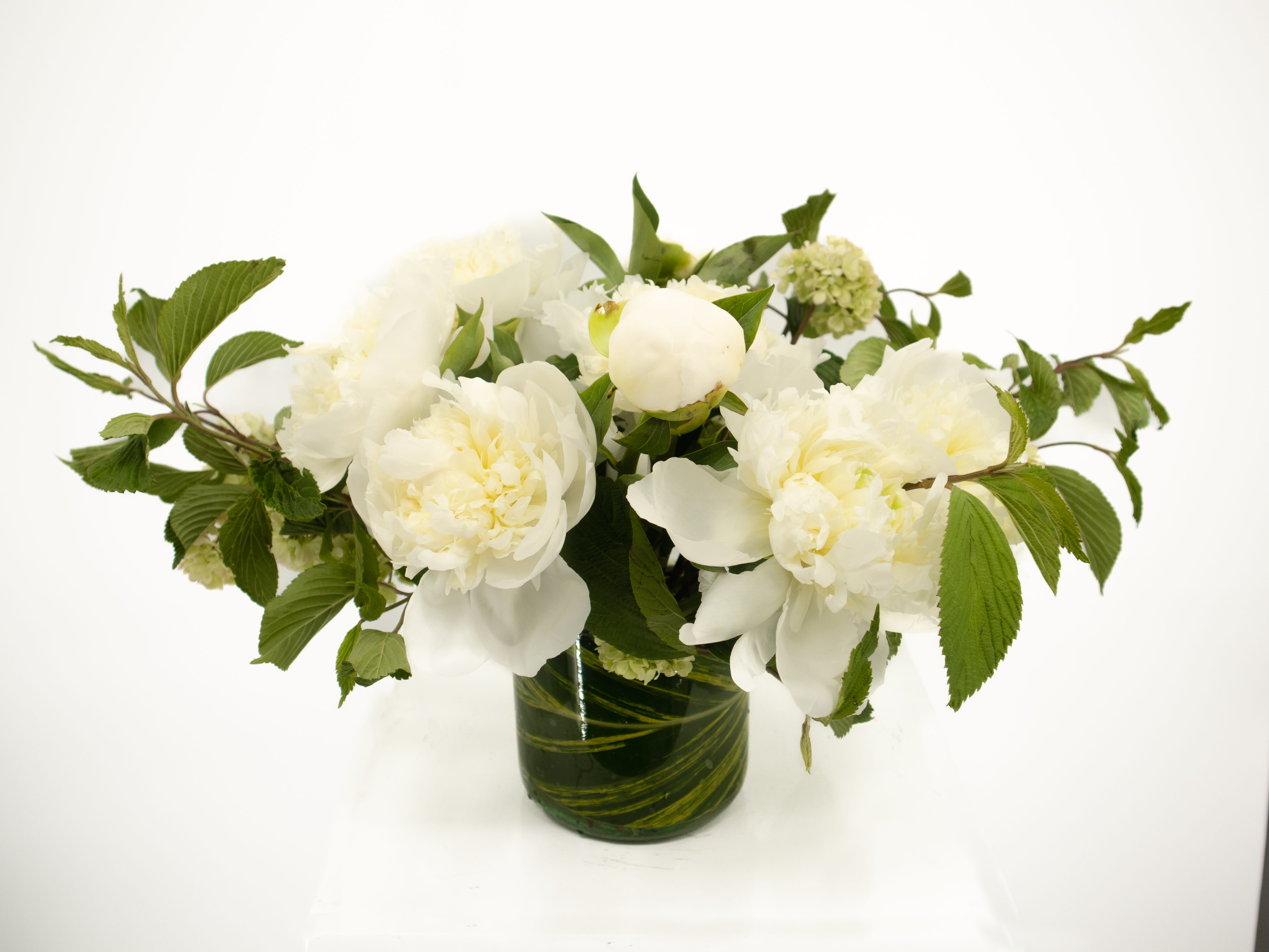 Betty  - A lush and impactful arrangement that will catch the attention of all who view it. This stunning piece is full of white seasonal peonies. With the added greenery this arrangement is sure to check all the boxes for any occasion.   *Peony color subject to availability 