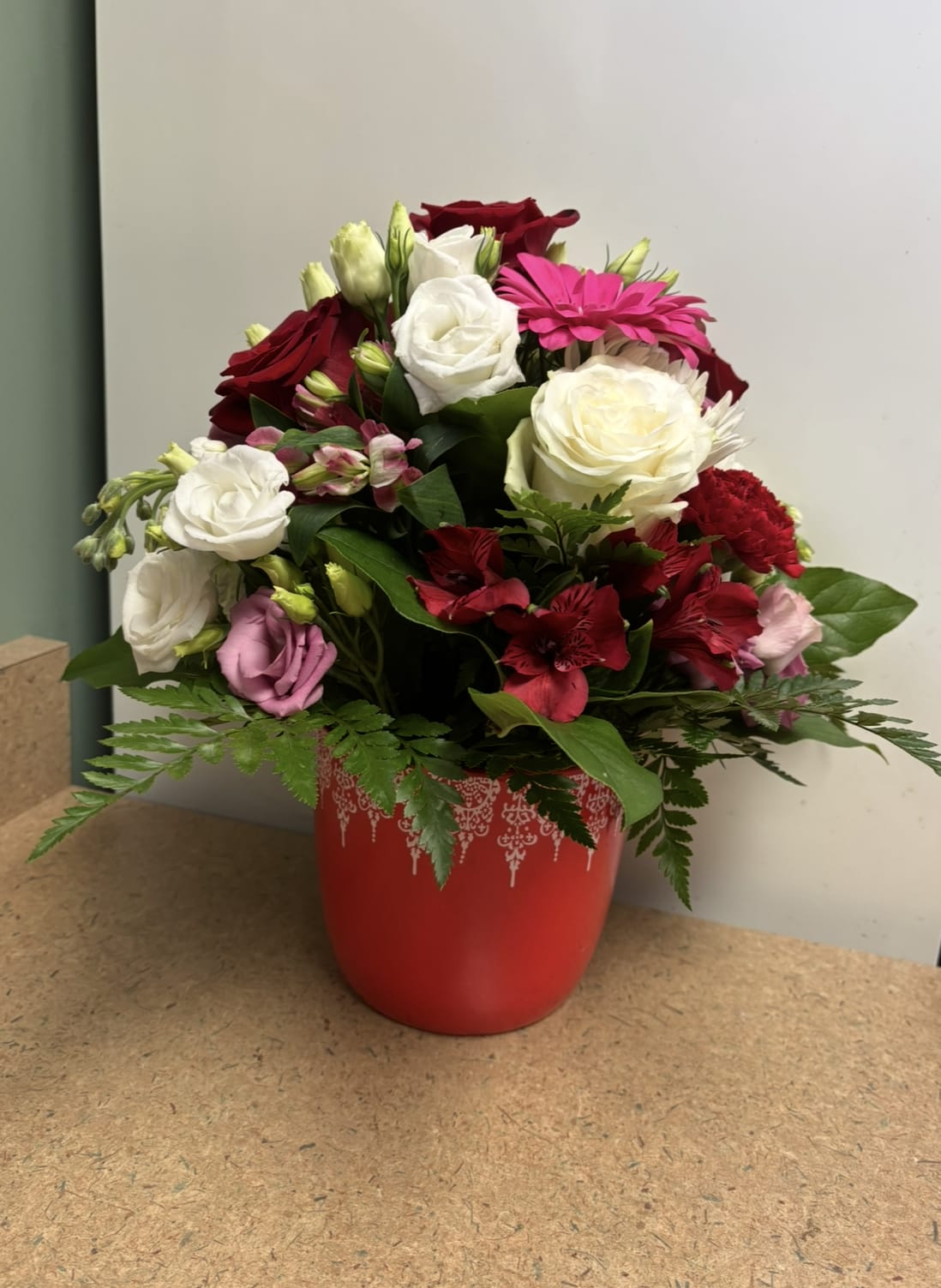 Victorian Spring - This romantic arrangement is designed in a collectable red ceramic vase with white lace design across the top.  It is filled with Designer chosen selections in the red, white, yellow, purple spring themed scheme.