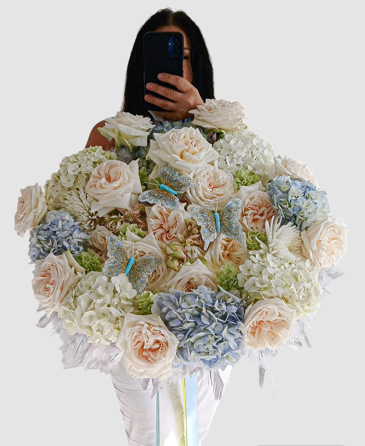 Mega Vanilla Rose Bouquet - Please call first for availability. Please allow 48 hours notice. Send this beautiful grand size fragrant bouquet today to show them how much you care with it's vast amount of vanilla garden roses blue and white hydrangeas and more arranged with grey feather accents a long flowing ribbon bow and butterflies. The ultimate flowers. Send beautiful!